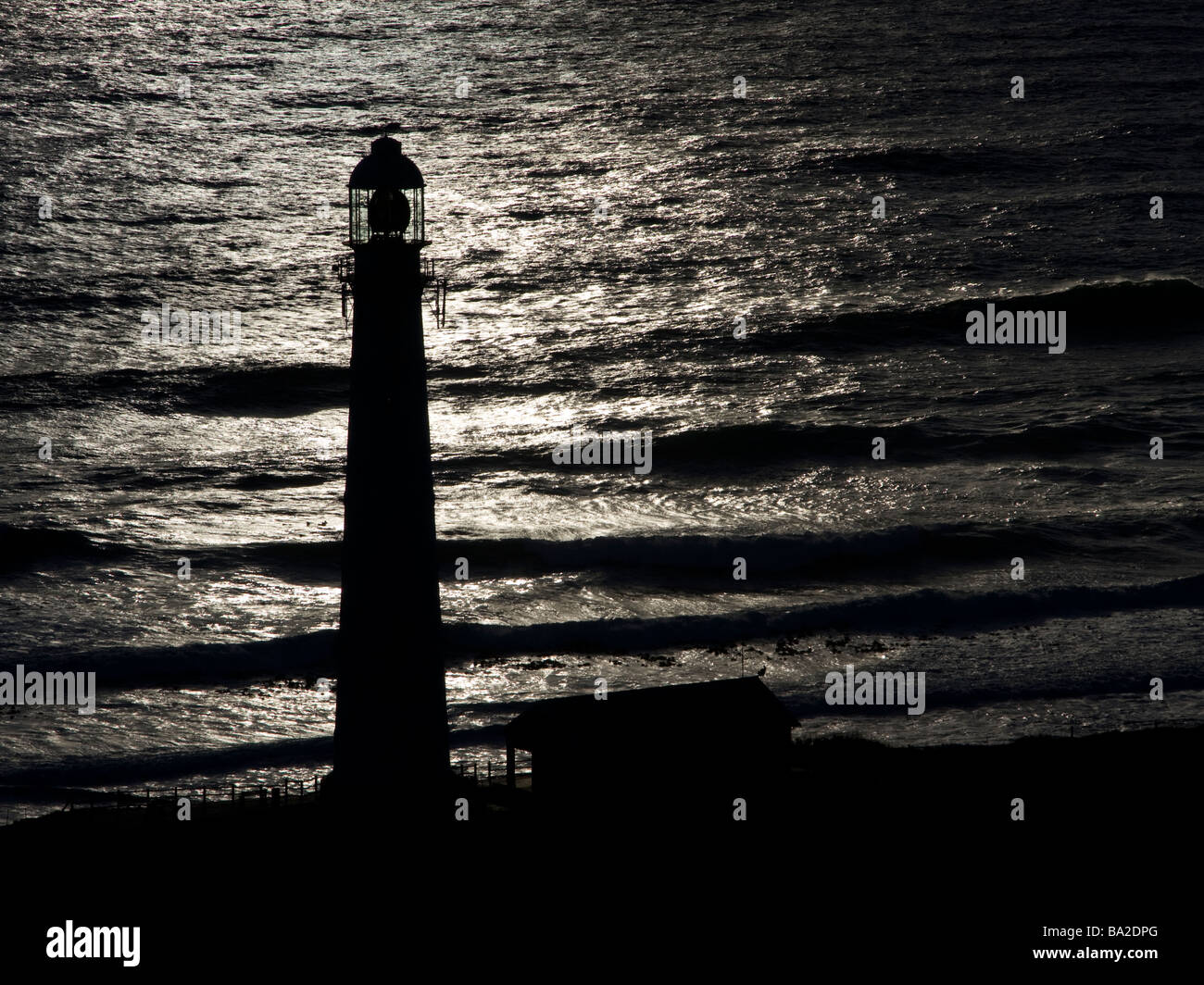 Slangkop Lighthouse Silhouetted against the Ocean at Dusk, Kommetjie Stock Photo