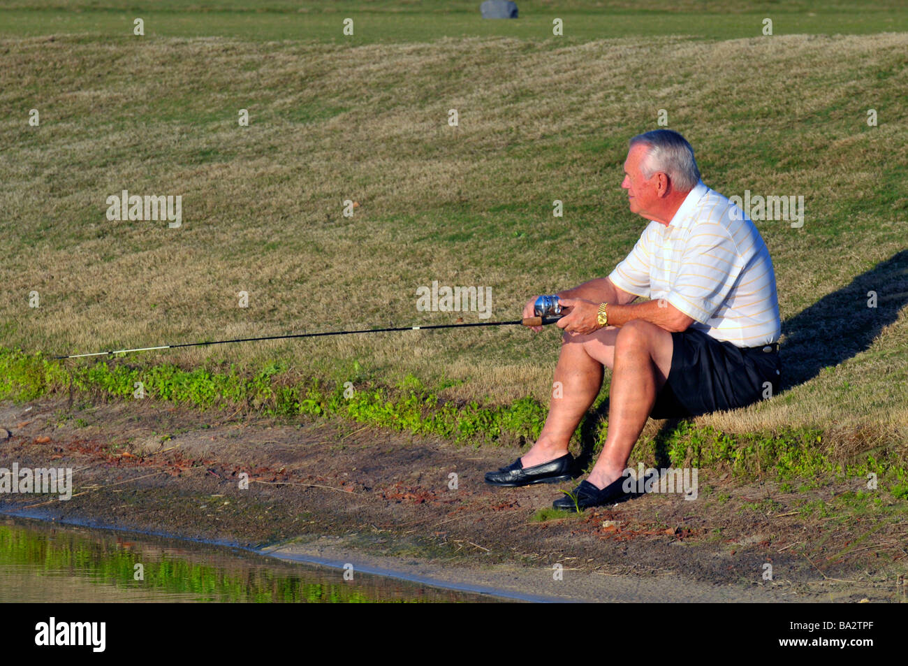 white male senior citizen fishes along pond Florida Stock Photo
