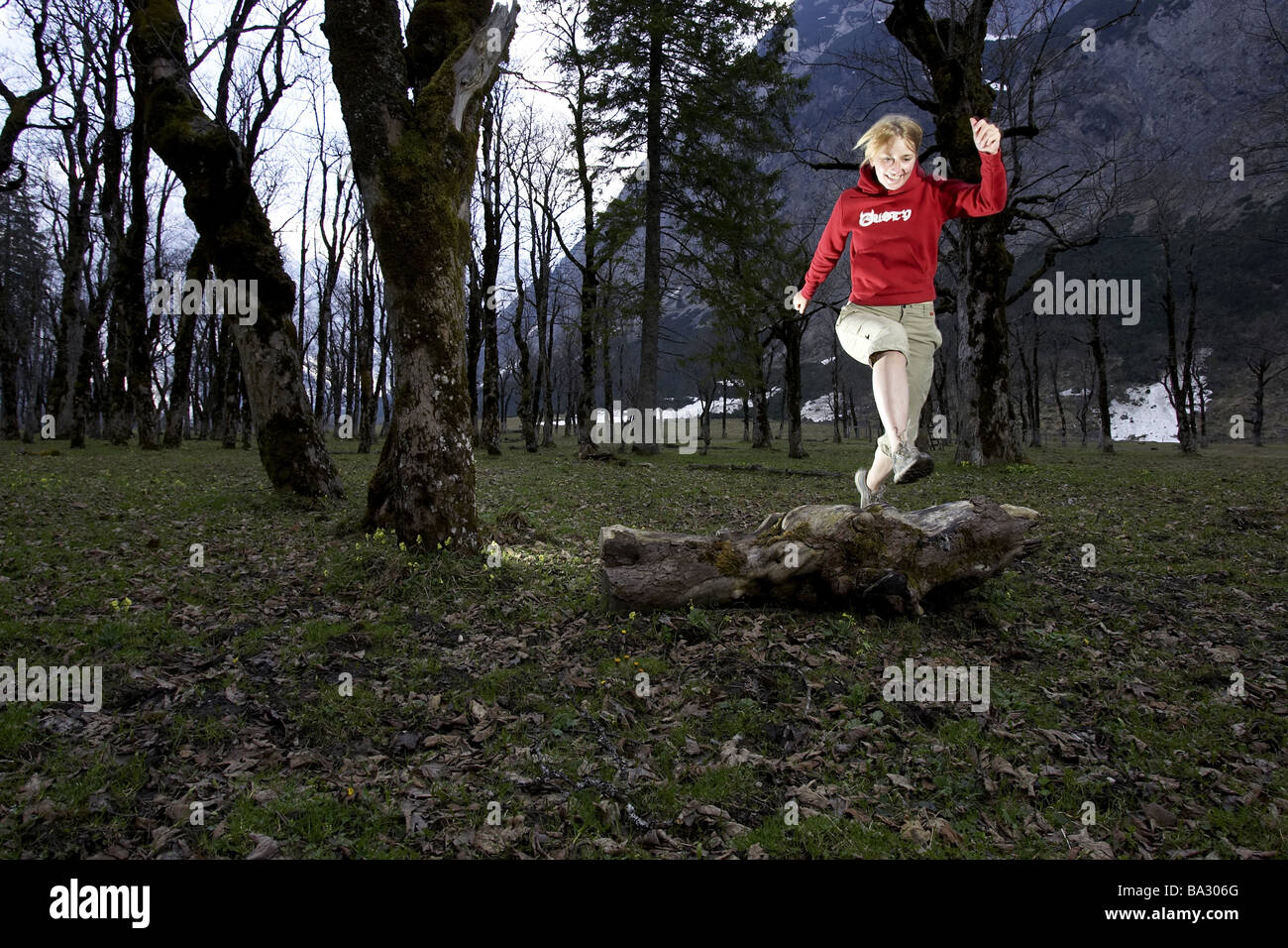 Woman young runs jump log forest series people 20-30 years quite-body blond leisurewear athletically movement runs activity Stock Photo