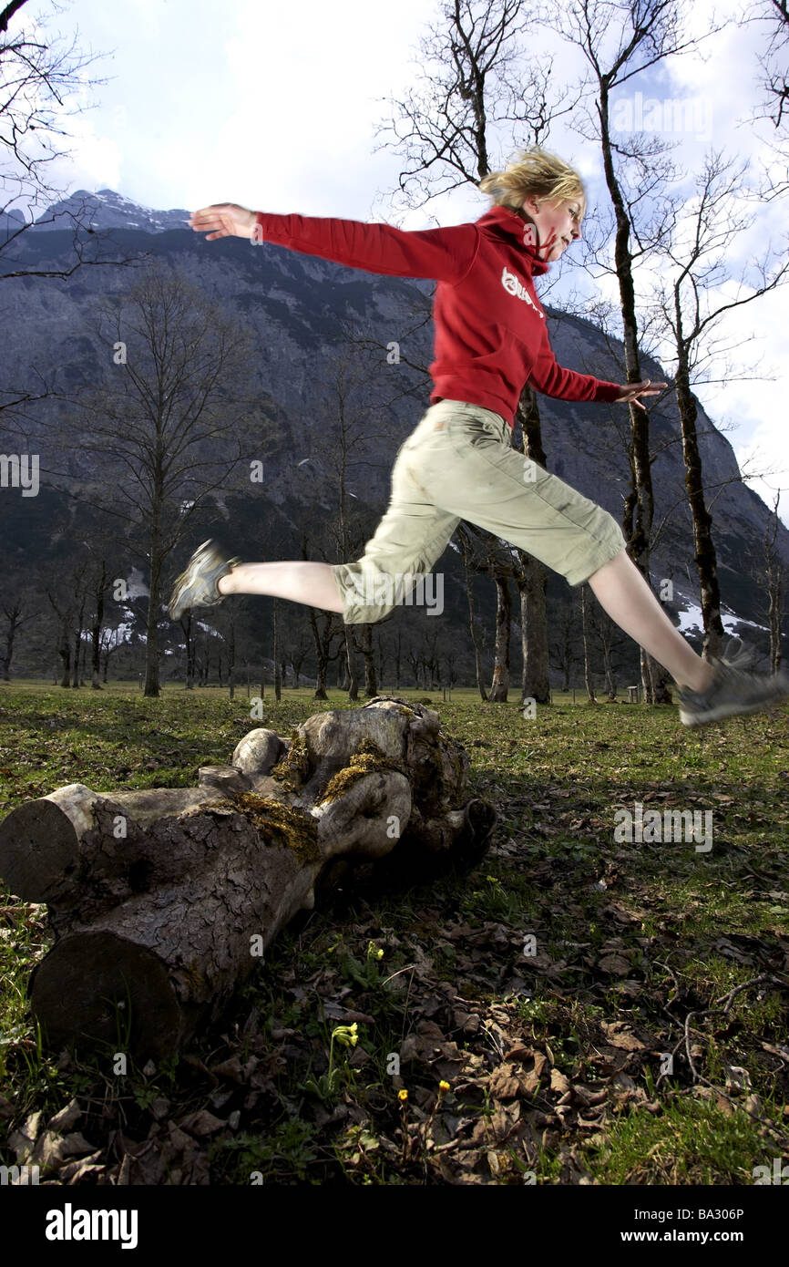 Woman young runs jump log at the side forest series people 20-30 years quite-bodies blond leisurewear athletically movement Stock Photo