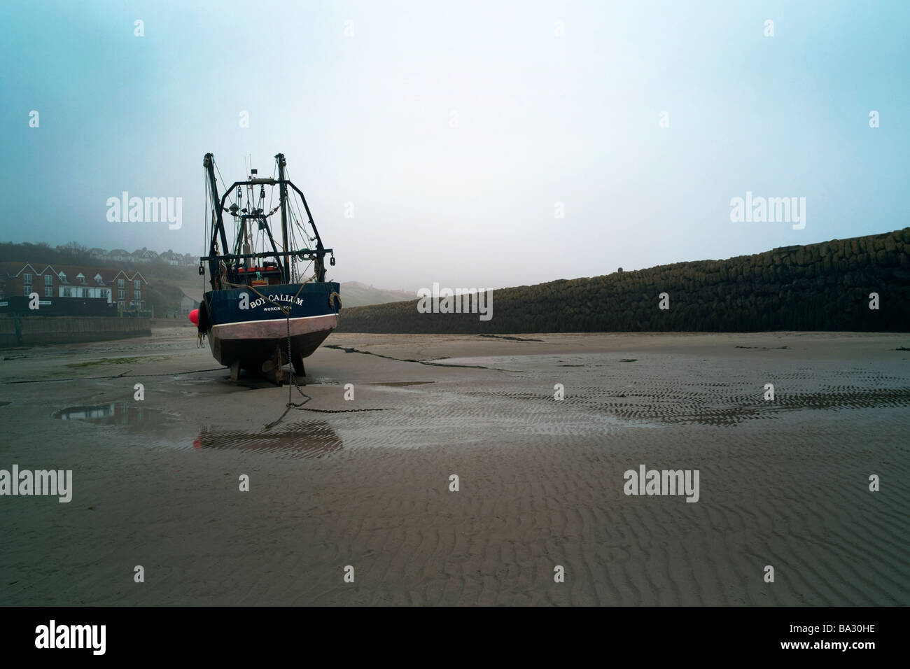 A fishing boat at low tide lying in Folkestone Harbour South East England Stock Photo