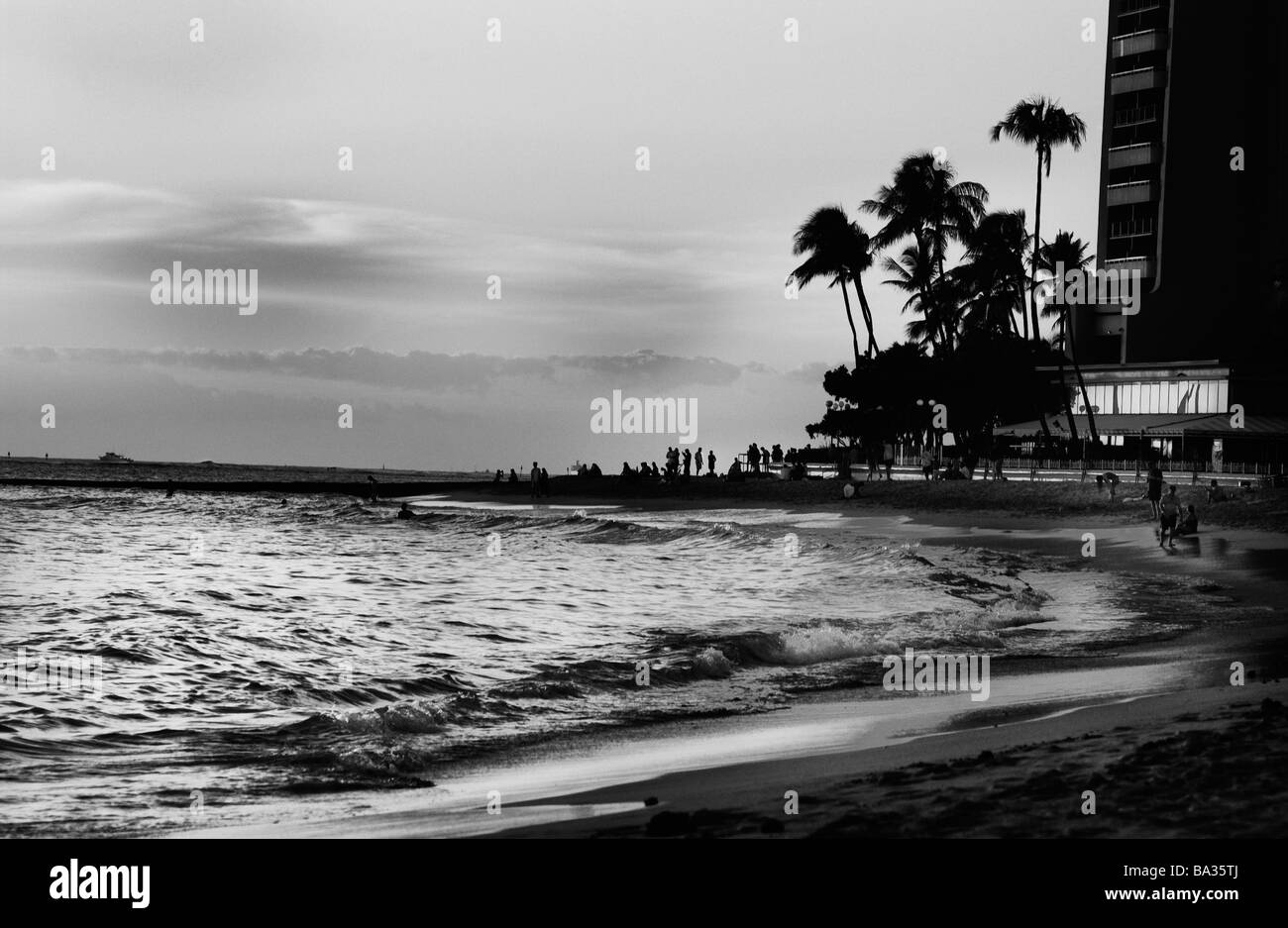 Sunset twilight silhouette at the beach of people vacationing  in Waikiki Hawaii. Stock Photo