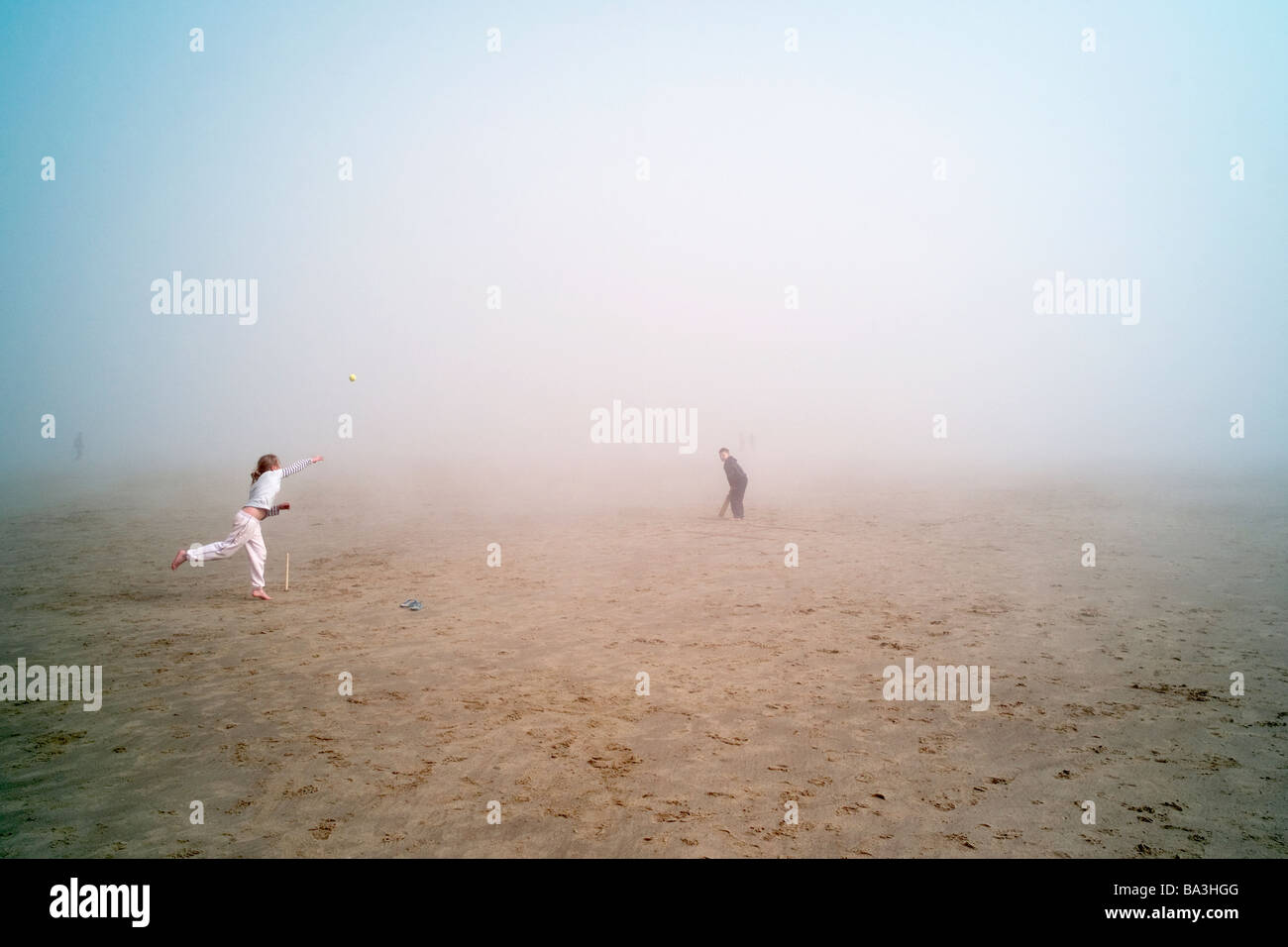 Children playing cricket on a fog bound beach in South East England Stock Photo