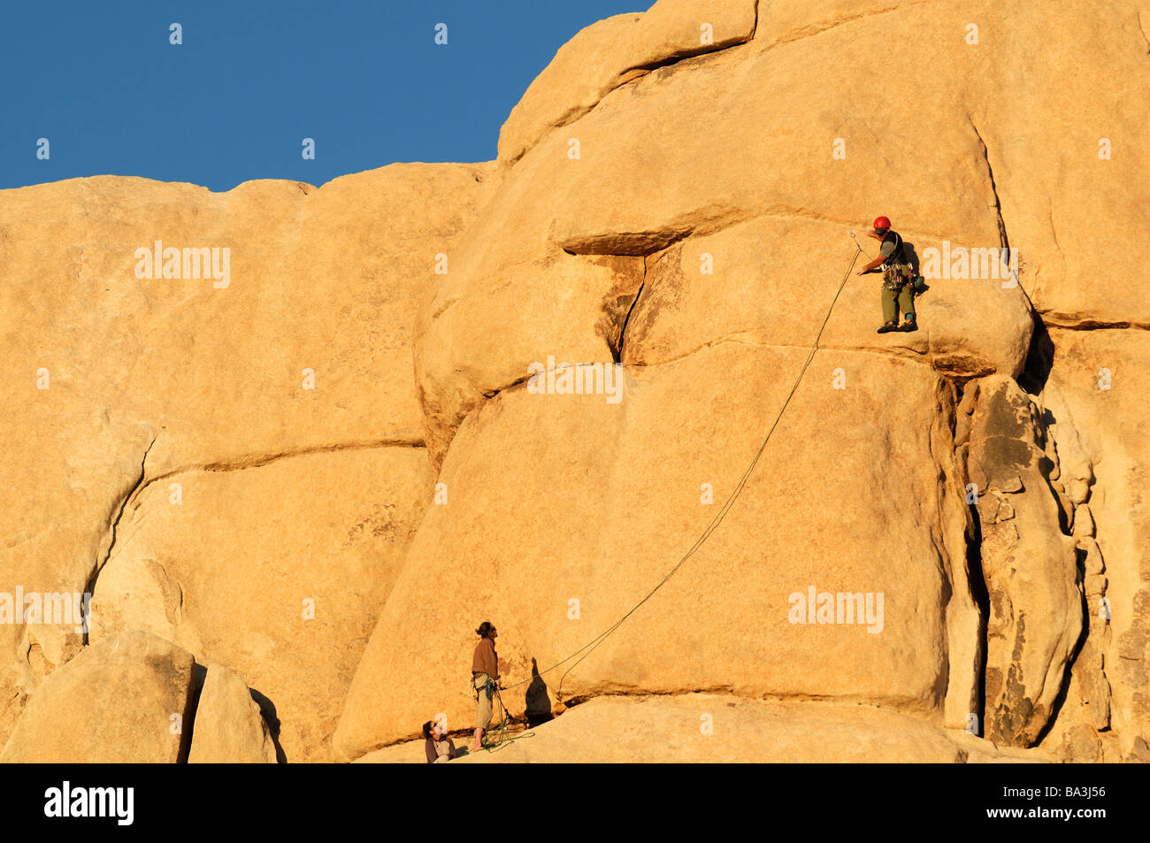 rock climber climbers getting ready to climb a rock wall face pinnacle Hidden Valley Joshua Tree National Park Stock Photo