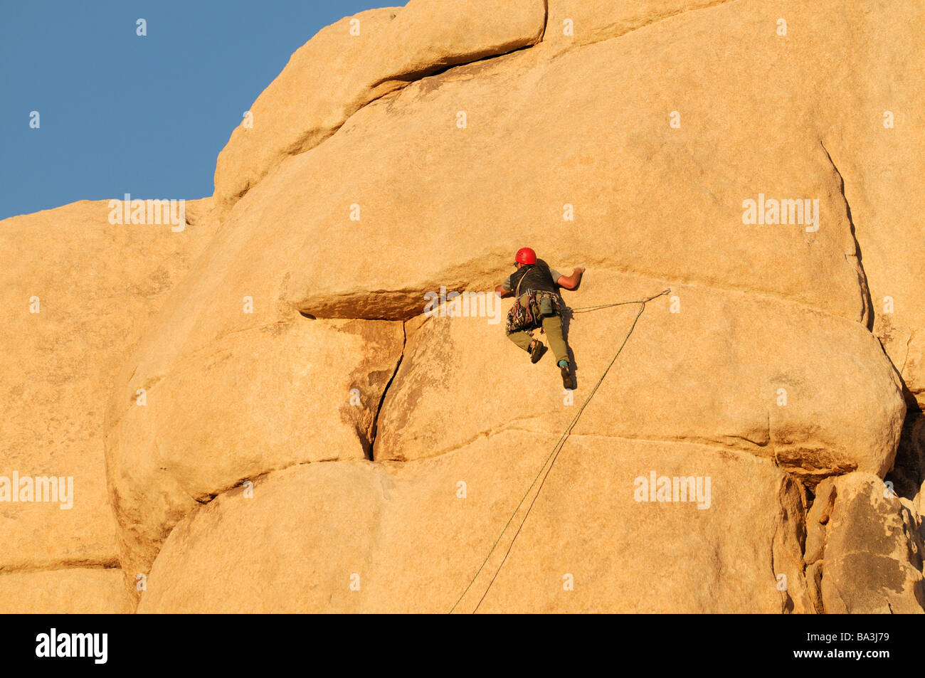one rock climber man getting ready to climb a rock wall face pinnacle Hidden Valley Joshua Tree National Park Stock Photo