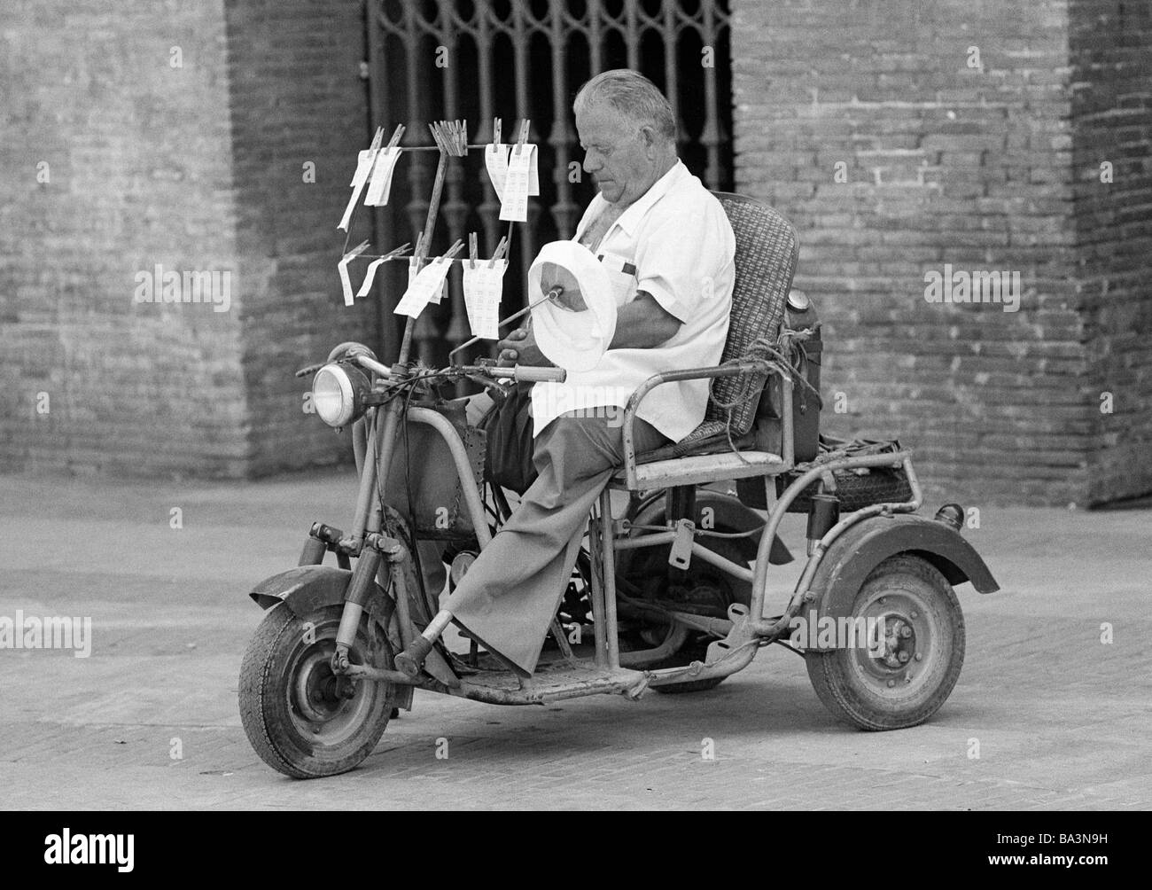 Seventies, black and white photo, people, poorness, gambling, ticket seller on a motorbike, physically handicapped, artificial leg, aged 50 to 70 years, Spain, Valencia Stock Photo