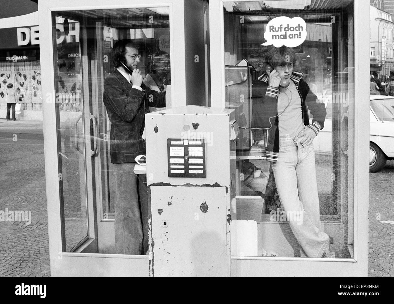 Seventies, black and white photo, people, communication, a man and a teenager phone from two telephone boxes located side by side, in front stands a letterbox, man, aged 30 to 40 years, boy, aged 16 to 20 years Stock Photo