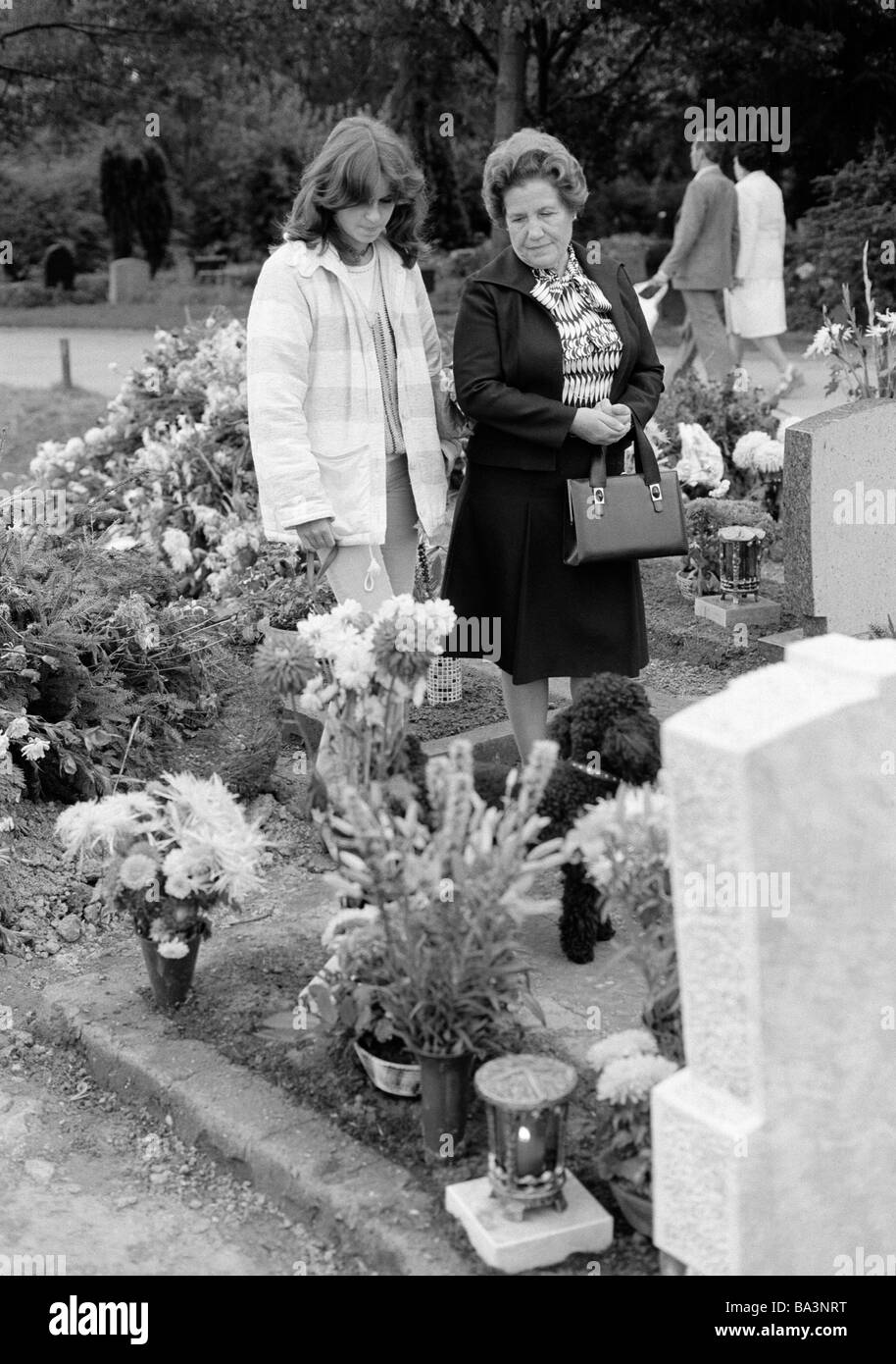 Seventies, black and white photo, people, death, mourning, churchyard, young girl and older woman stand at a tomb, flowers, aged 16 to 18 years, aged 60 to 70 years, Birgit, Frieda Stock Photo