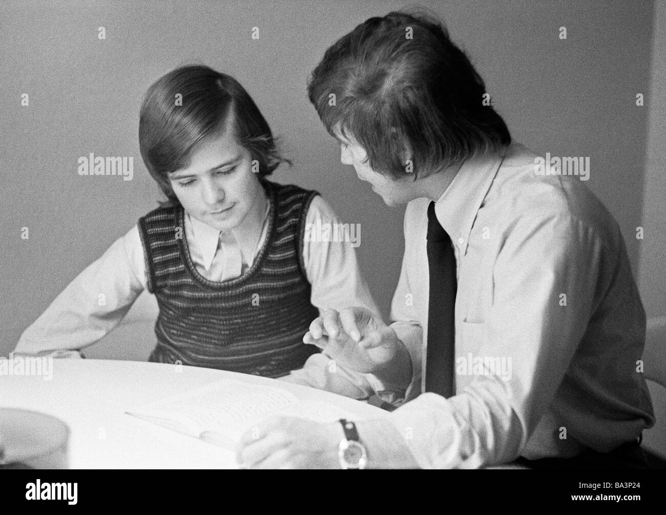 Seventies, black and white photo, people, young boy during homework, his father sits side by side and declares the tasks, aged 14 to 17 years, aged 35 to 40 years Stock Photo