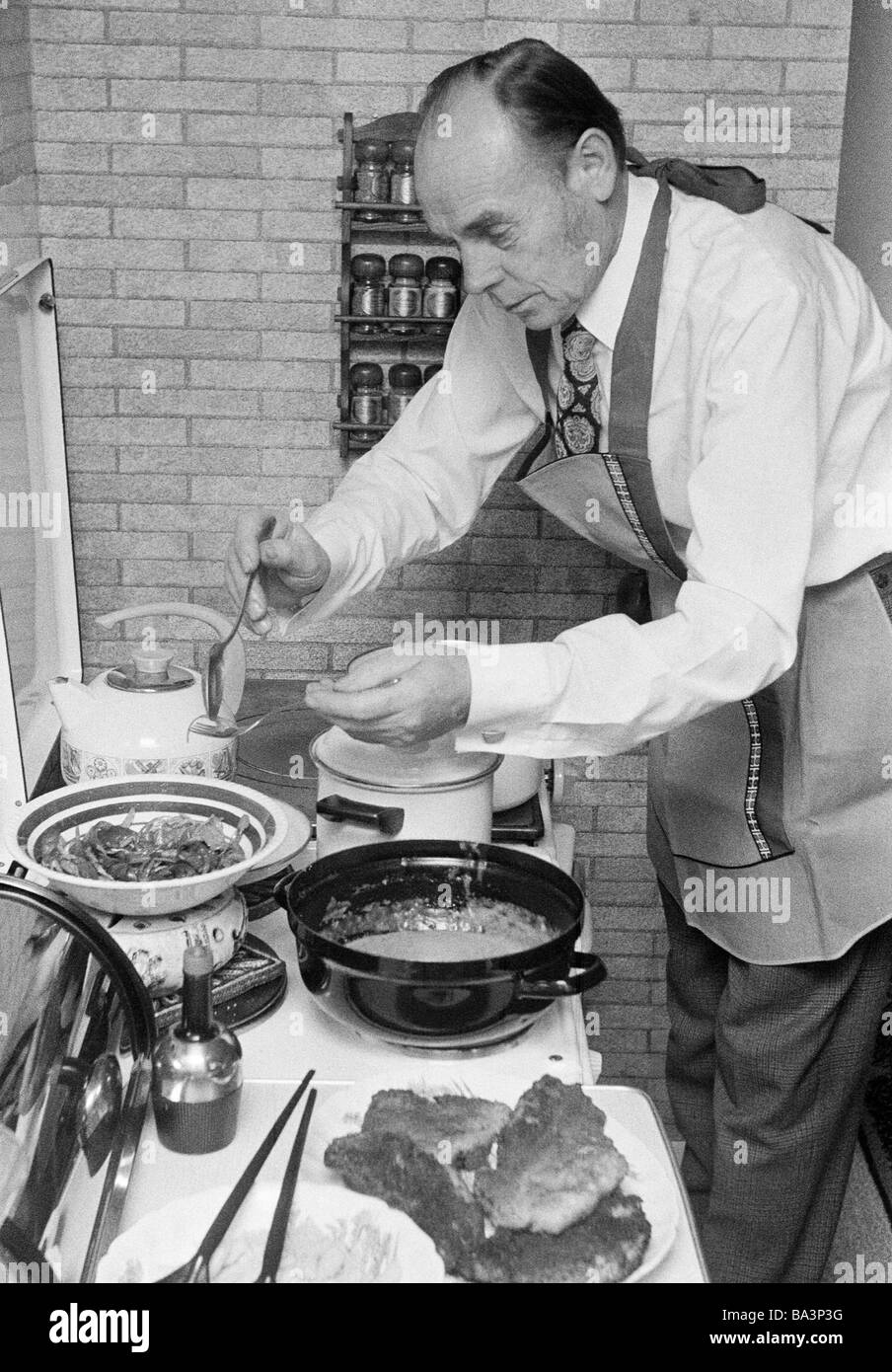 Seventies, black and white photo, people, older man stands at the cooking-stove and prepares the food, aged 60 to 70 years, Josef Stock Photo