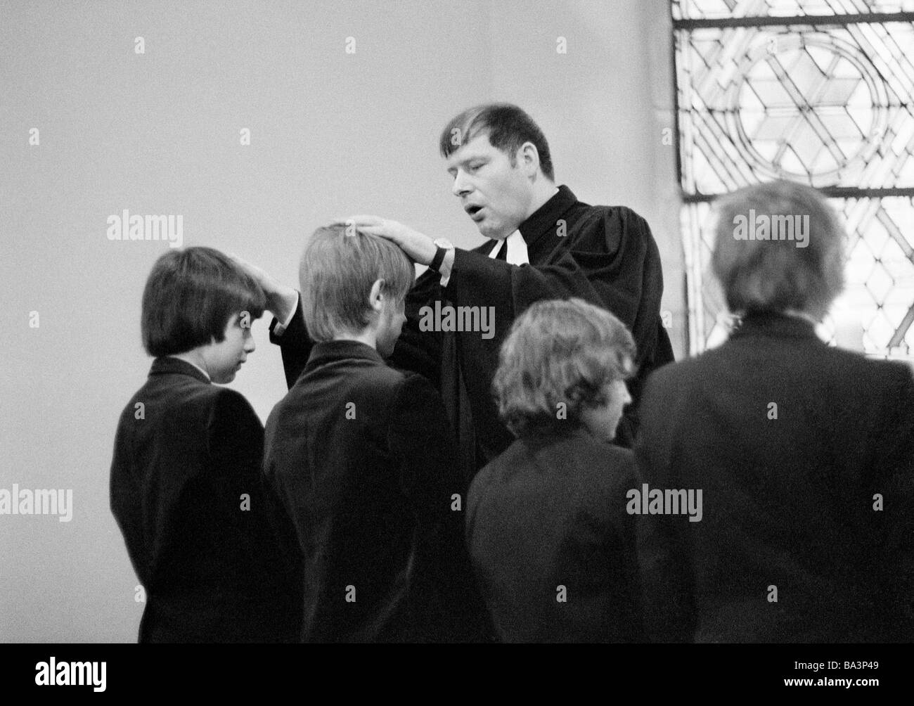 Seventies, black and white photo, religion, Christianity, confirmation, priest confirms the confirmees by laying on of hands, boys, aged 13 to 16 years, aged 35 to 40 years Stock Photo