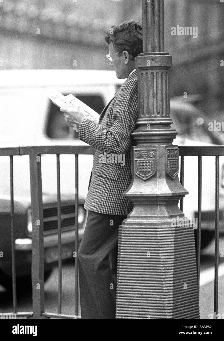 Seventies, black and white photo, people, man abut on a lamppost reads a newspaper, aged 40 to 50 years, Great Britain, England, London Stock Photo