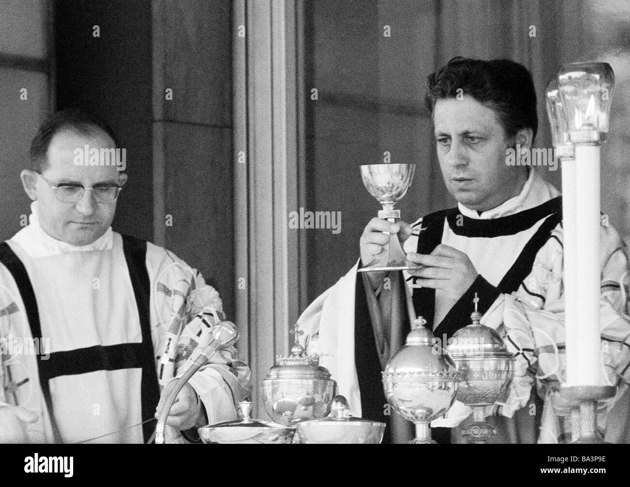 Seventies, black and white photo, religion, Christianity, holy mass, Eucharist, priest holds the communion cup, aside an acolyte, aged 40 to 50 years Stock Photo