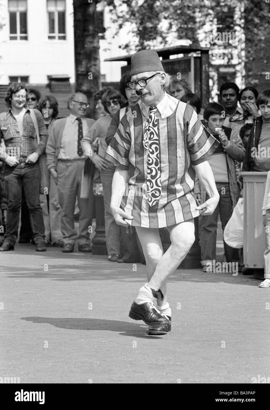 Seventies, black and white photo, humour, people, visitors on a sqare have fun with a costumed comedian, aged 60 to 70 years, Great Britain, England, London Stock Photo