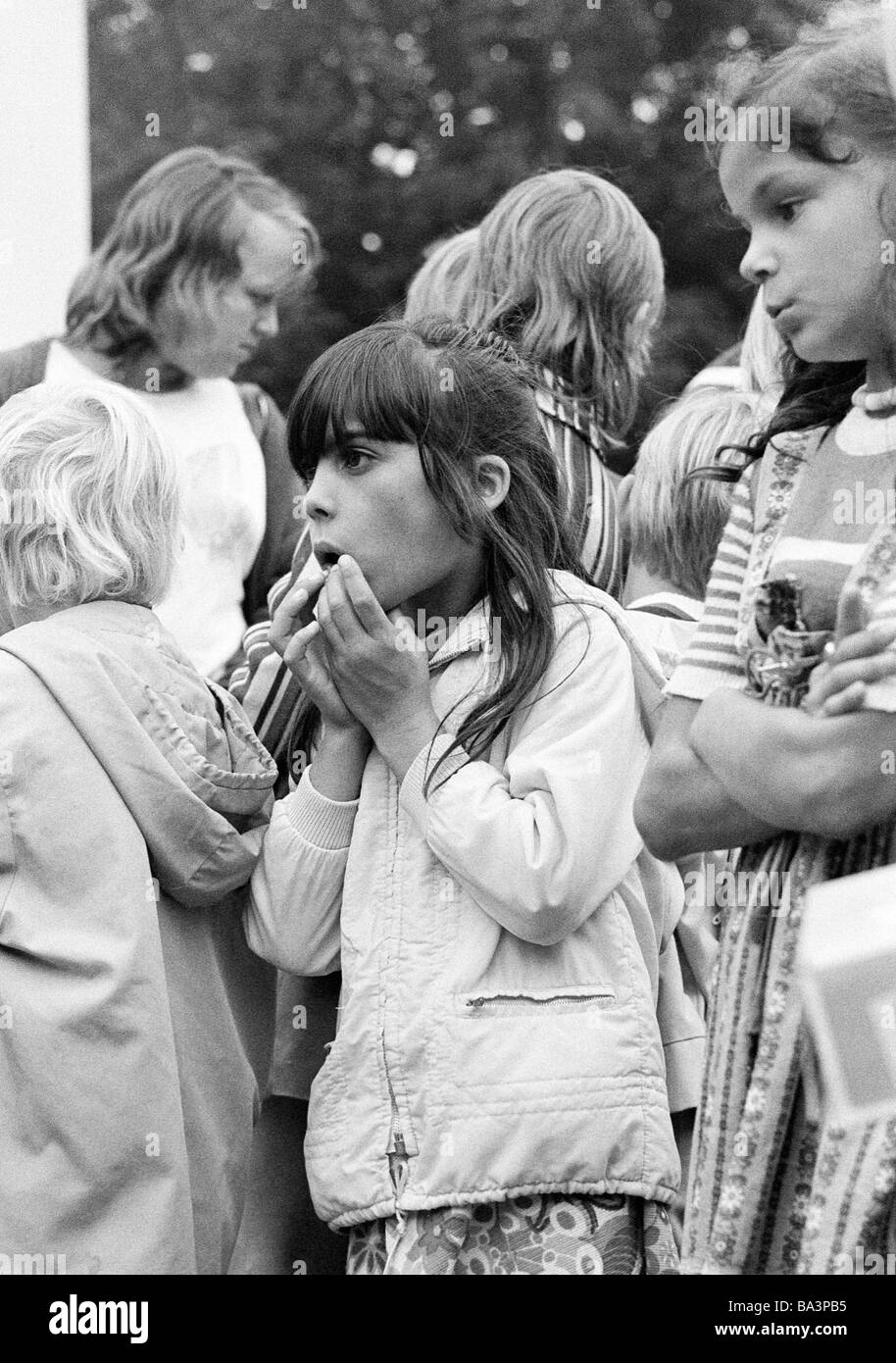 Seventies, black and white photo, people, children, childrens treat, little girl is charmed about a show, aged 5 to 8 years, other children looking bored, opposite between interest and disinterest Stock Photo