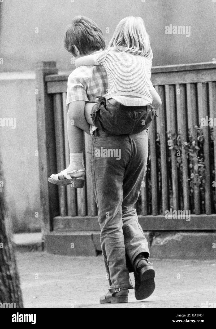 Seventies, black and white photo, people, children, boy bears a little girl piggyback, aged 10 to 13 years, aged 5 to 7 years Stock Photo