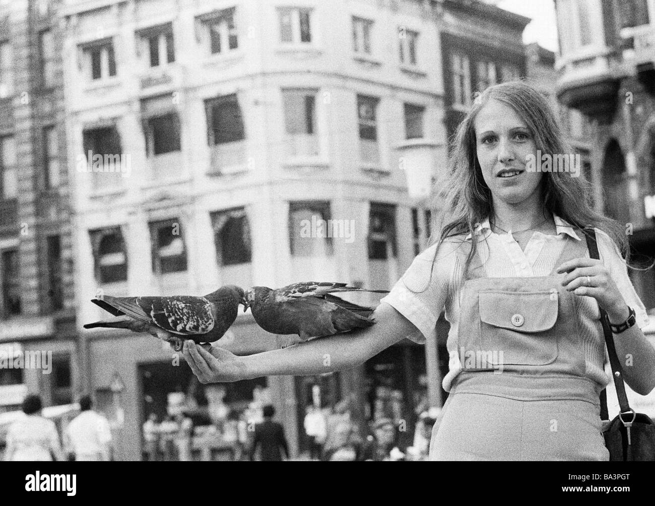 Seventies, black and white photo, people, two pigeons sitting on the arm of a young woman, aged 25 to 30 years, blouse, trousersuit, freetime, Netherlands, Amsterdam Stock Photo