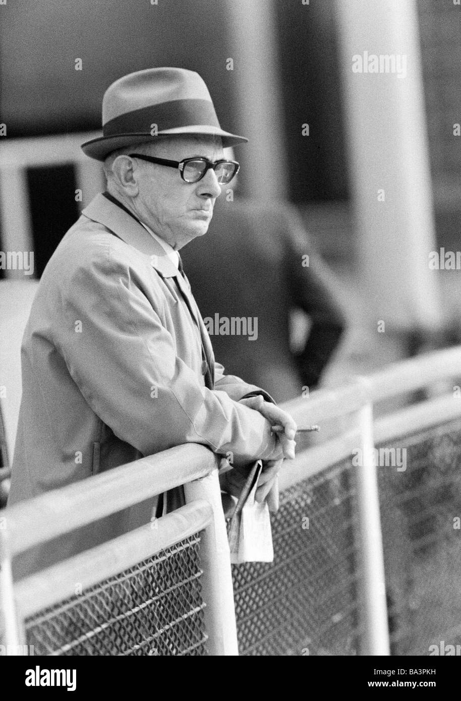 Seventies, black and white photo, sports, equestrianism, racecourse Dinslaken, trotting race 1973, horse-racing bet, man holds a racing sheet in his hands and looks critical to the trotters, aged 65 to 75 years, D-Dinslaken, Lower Rhine, Ruhr area, North Rhine-Westphalia Stock Photo
