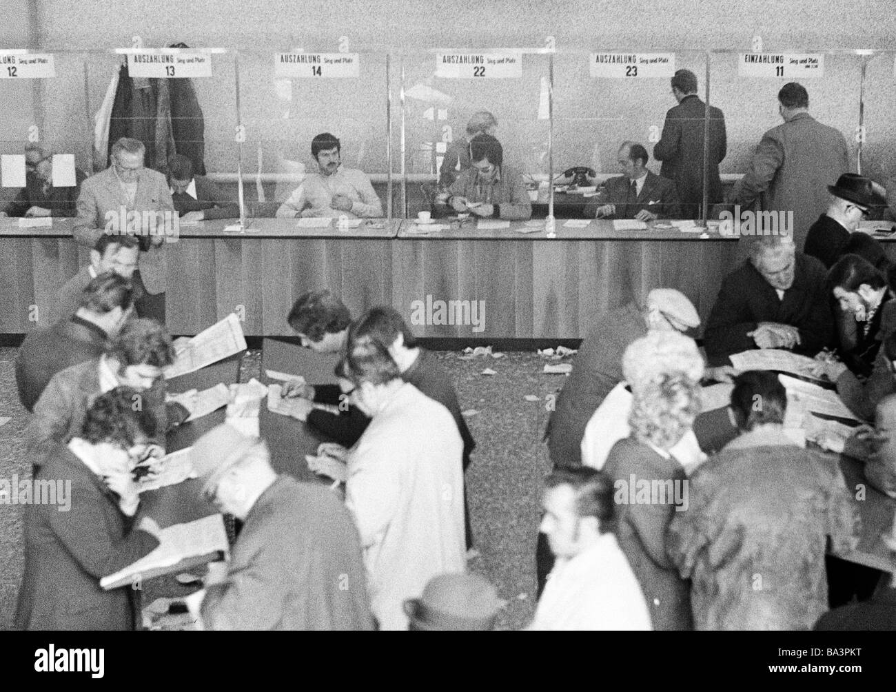 Seventies, black and white photo, sports, equestrianism, racecourse Dinslaken, trotting race 1973, horse-racing bet, bet counters, men and women read the racing sheet, D-Dinslaken, Lower Rhine, Ruhr area, North Rhine-Westphalia Stock Photo