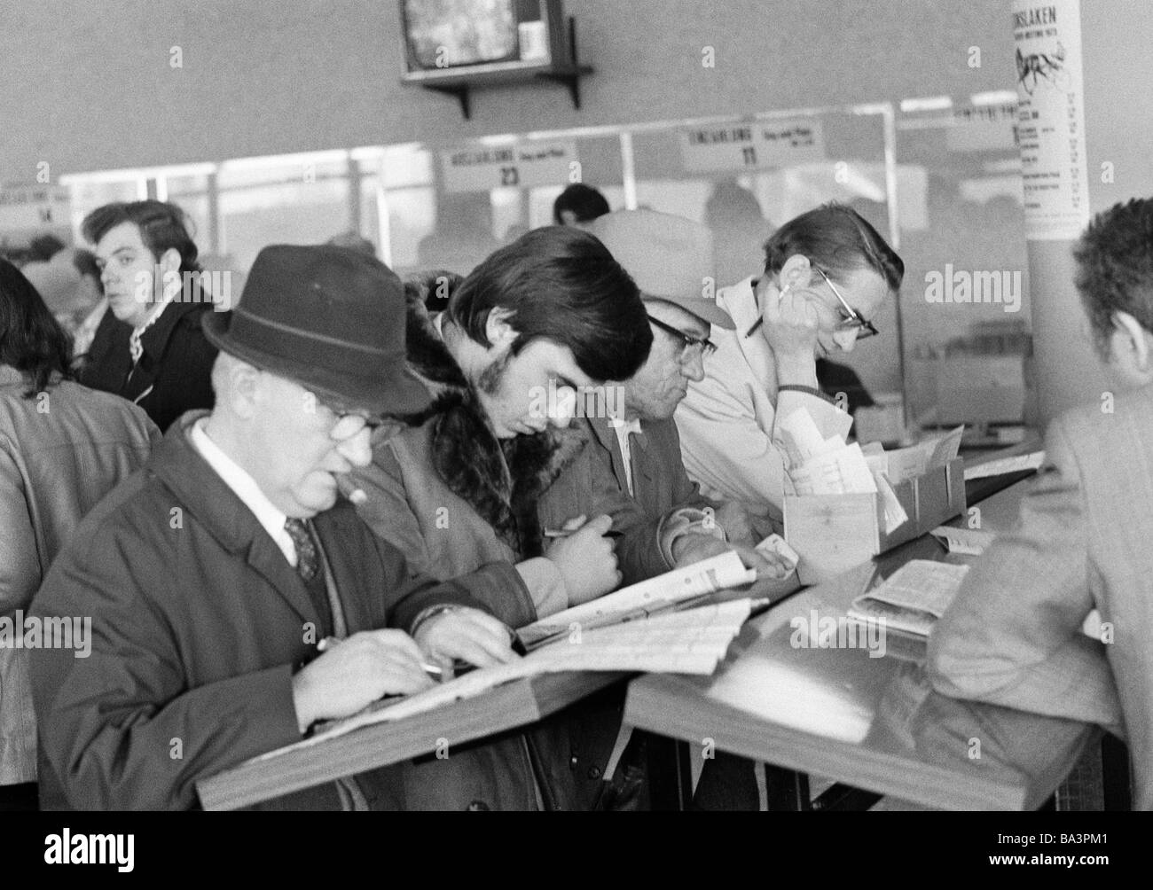 Seventies, black and white photo, sports, equestrianism, racecourse Dinslaken, trotting race 1973, horse-racing bet, men read the racing sheet, aged 25 to 30 years, aged 40 to 50 years, aged 60 to 70 years, D-Dinslaken, Lower Rhine, Ruhr area, North Rhine-Westphalia Stock Photo