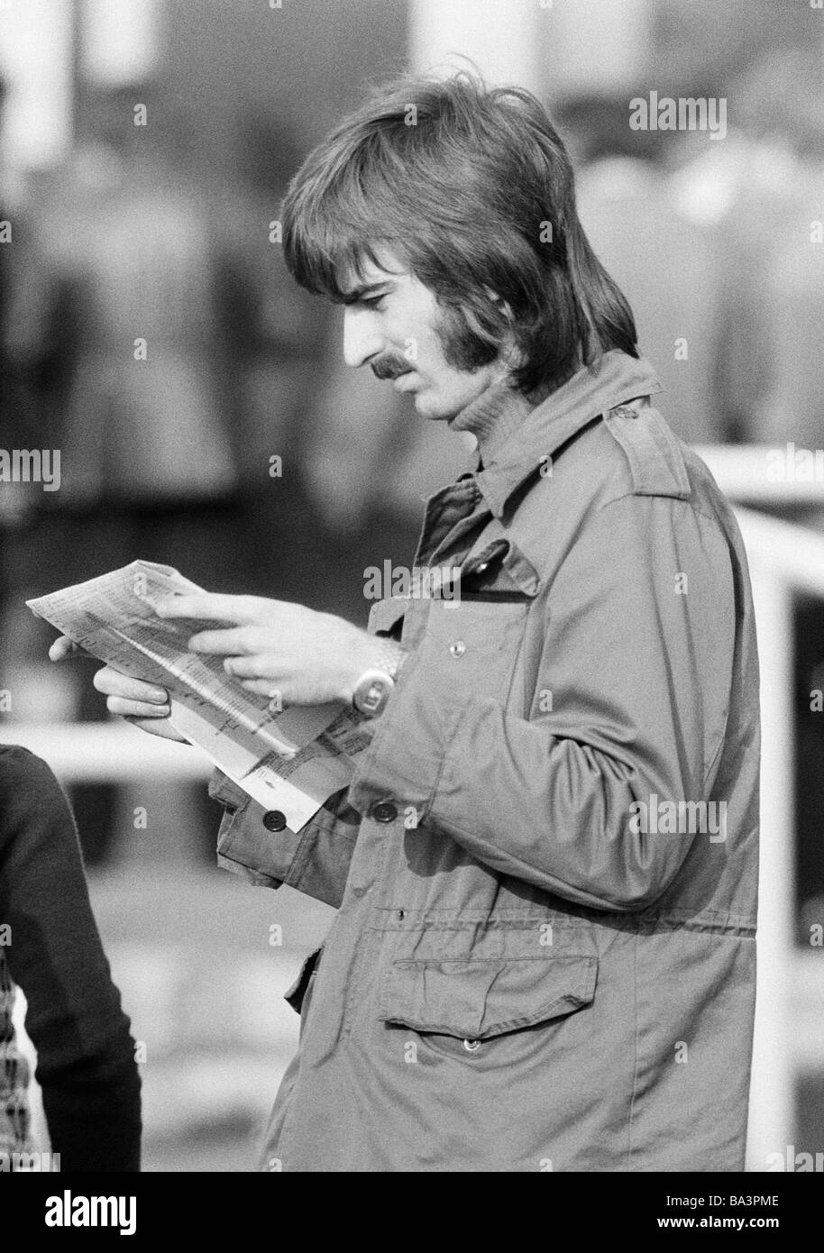 Seventies, black and white photo, sports, equestrianism, racecourse Dinslaken, trotting race 1973, horse-racing bet, man reads the racing sheet, aged 20 to 25 years, D-Dinslaken, Lower Rhine, Ruhr area, North Rhine-Westphalia Stock Photo