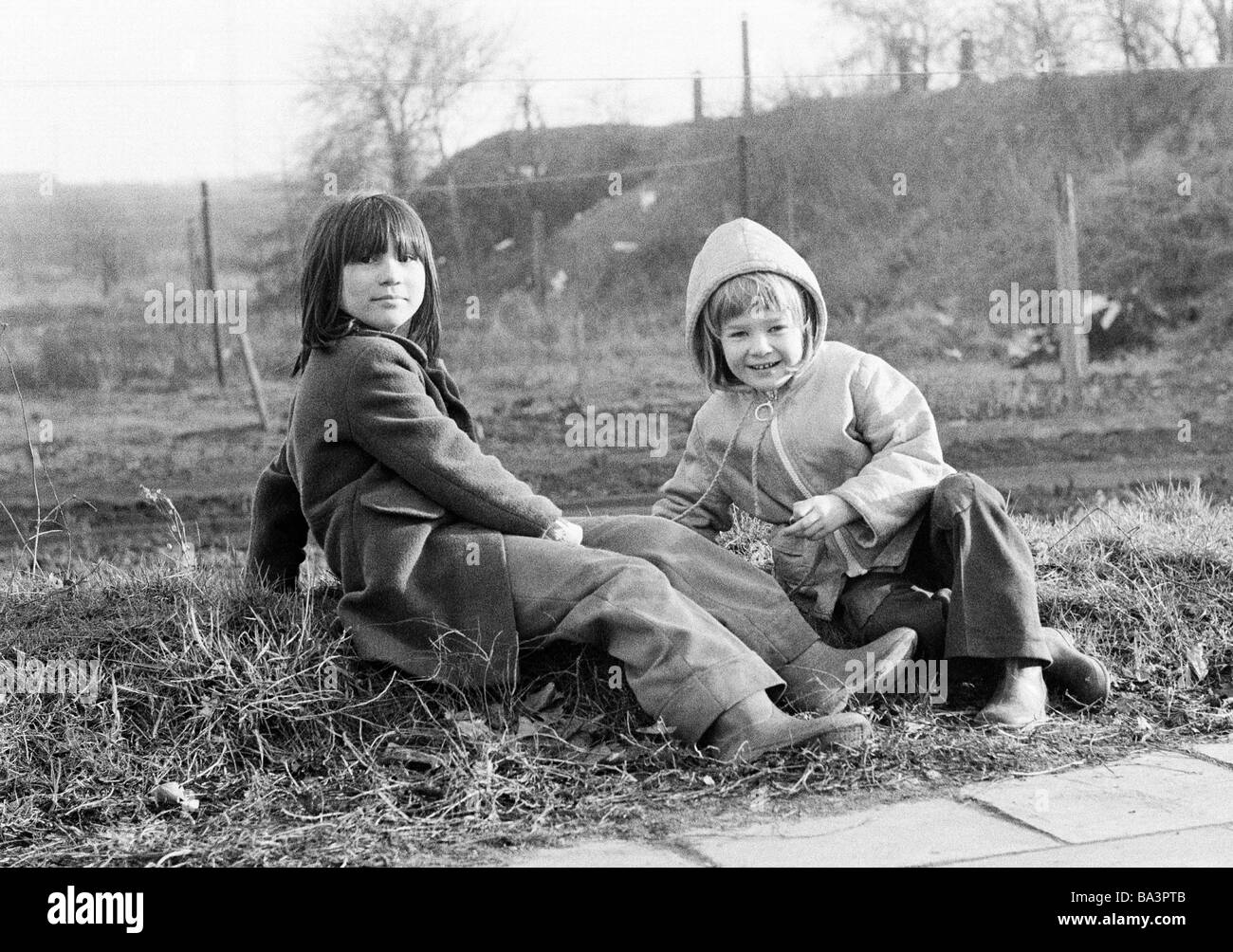 Seventies, black and white photo, people, children, two little girls sit in the grass, aged 5 to 10 years Stock Photo