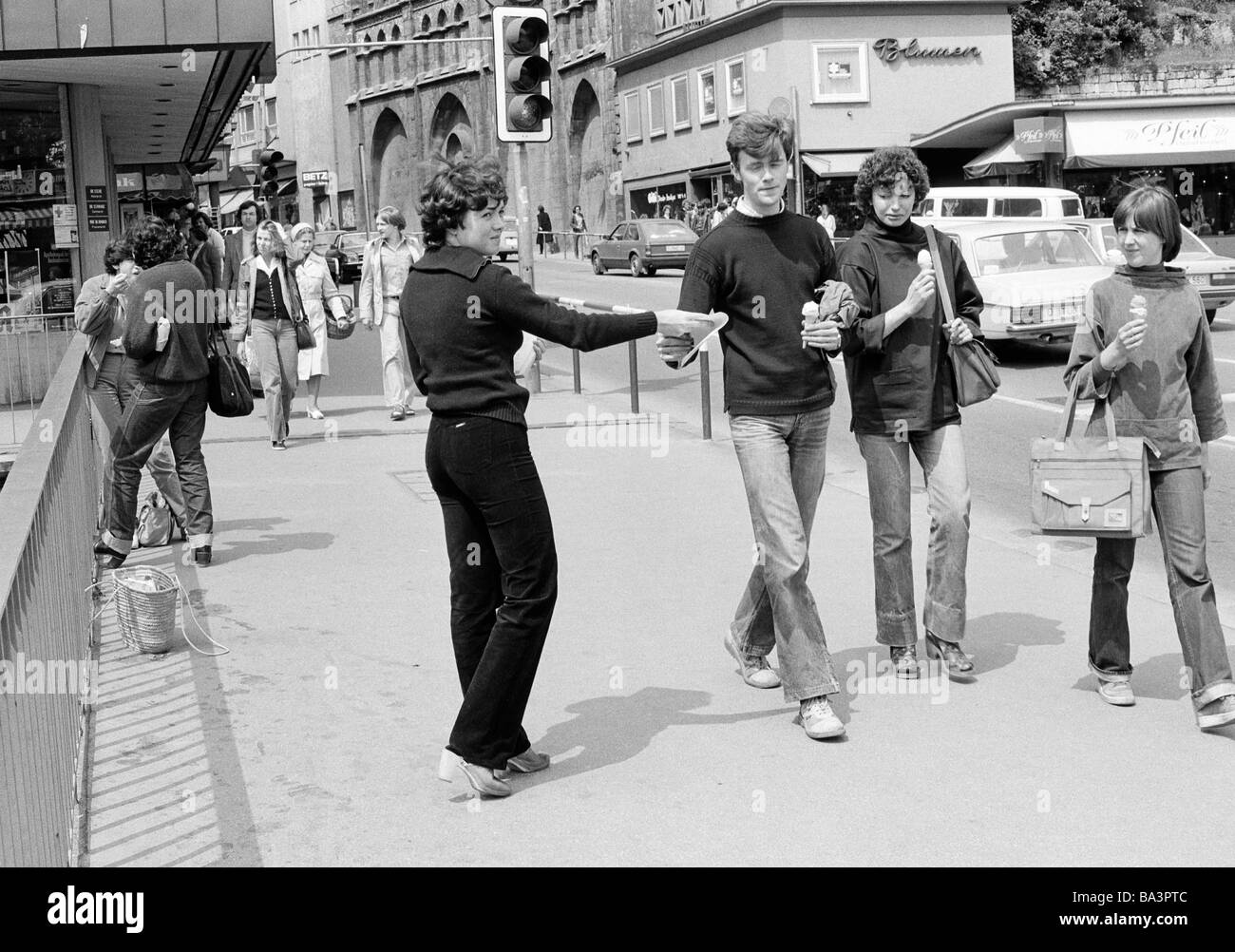 Eighties, black and white photo, people, opinion-forming, advertising, young woman handing out flyers to passersby walking on a pavement, D-Tuebingen, Neckar, Steinlach, Ammer, Schoenbuch, Baden-Wuerttemberg Stock Photo
