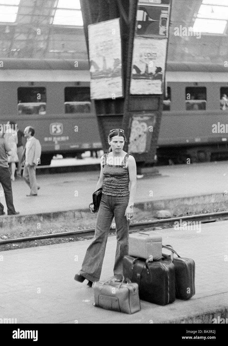 Seventies, black and white photo, railway station, Milan Central Station, young woman stands on the platform and is waiting for the train, suitcases, travel bag, aged 25 to 30 years, Italy, Lombardy, Milan Stock Photo