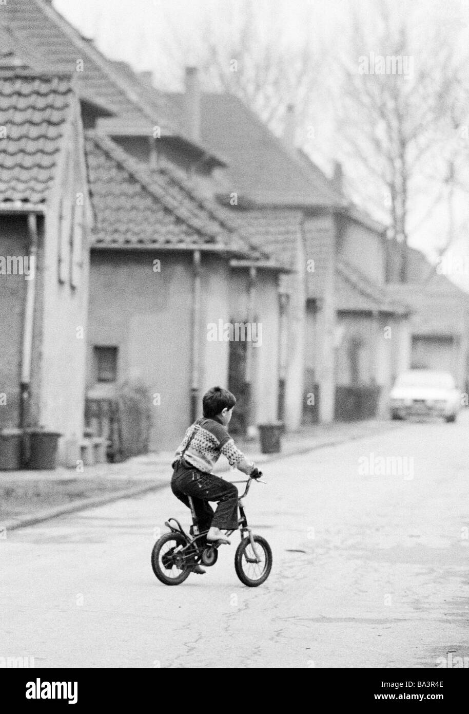 Eighties, black and white photo, people, children, little boy drives on a childrens bicycle across a traffic street, mining settlement, Ruhr area, aged 4 to 7 years Stock Photo