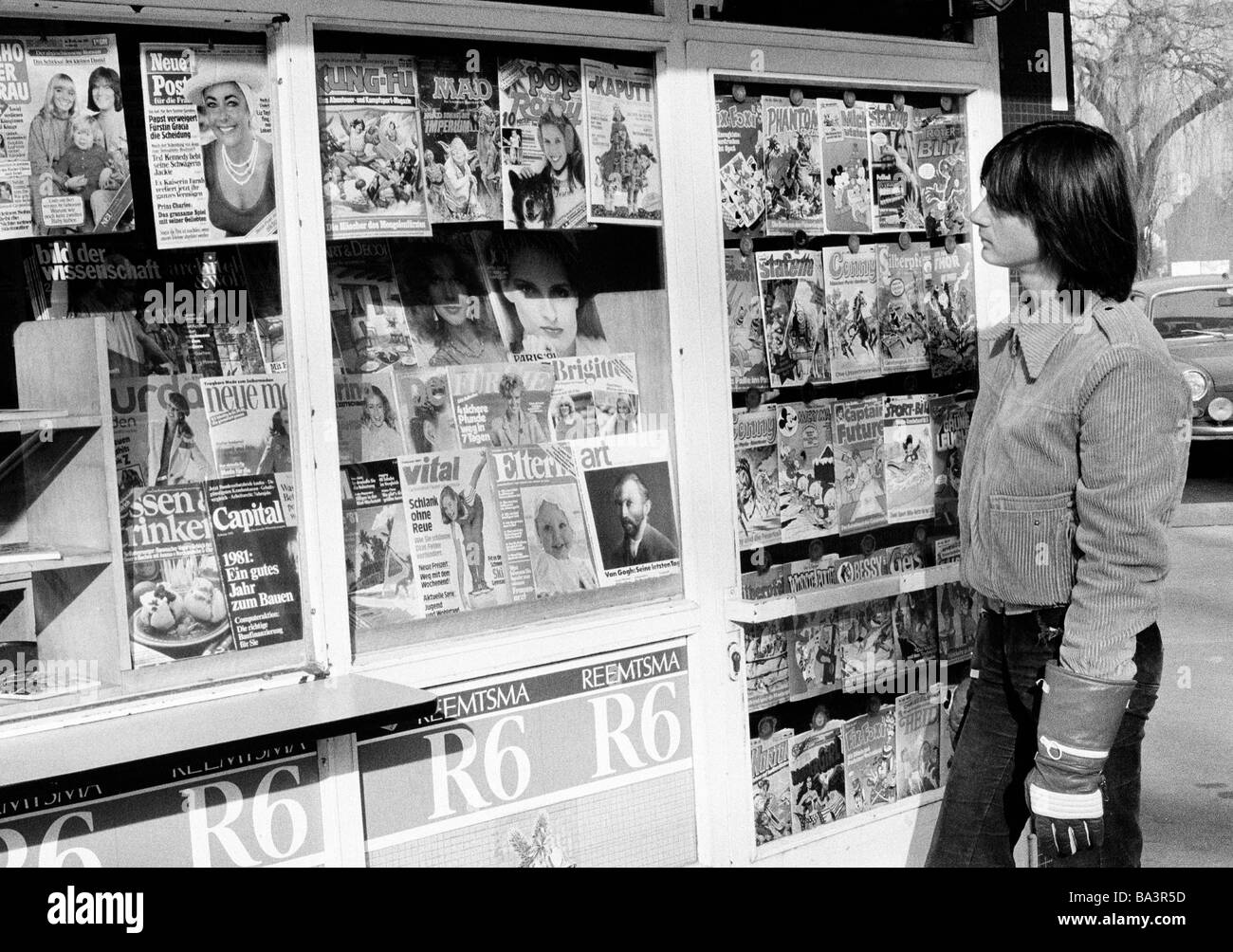 Eighties, black and white photo, people, young boy at a kiosk looking to the magazines, leisurewear, jacket, leather gloves, aged 16 to 20 years Stock Photo