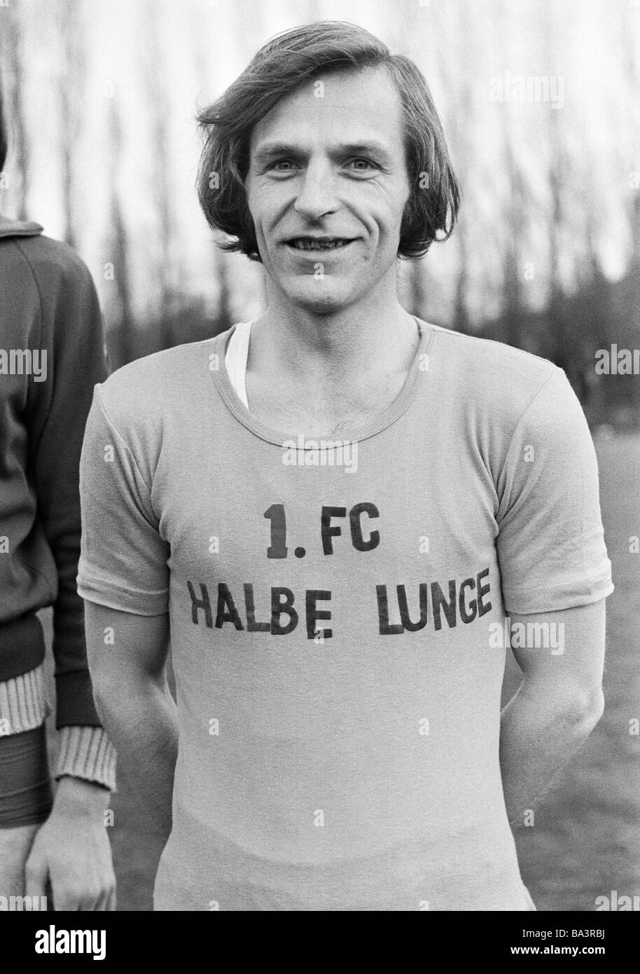Seventies, black and white photo, people, recreational sport, health, fitness, humour, man posing in a tricot with the inscription '1. FC Half Lungs', aged 30 to 40 years Stock Photo