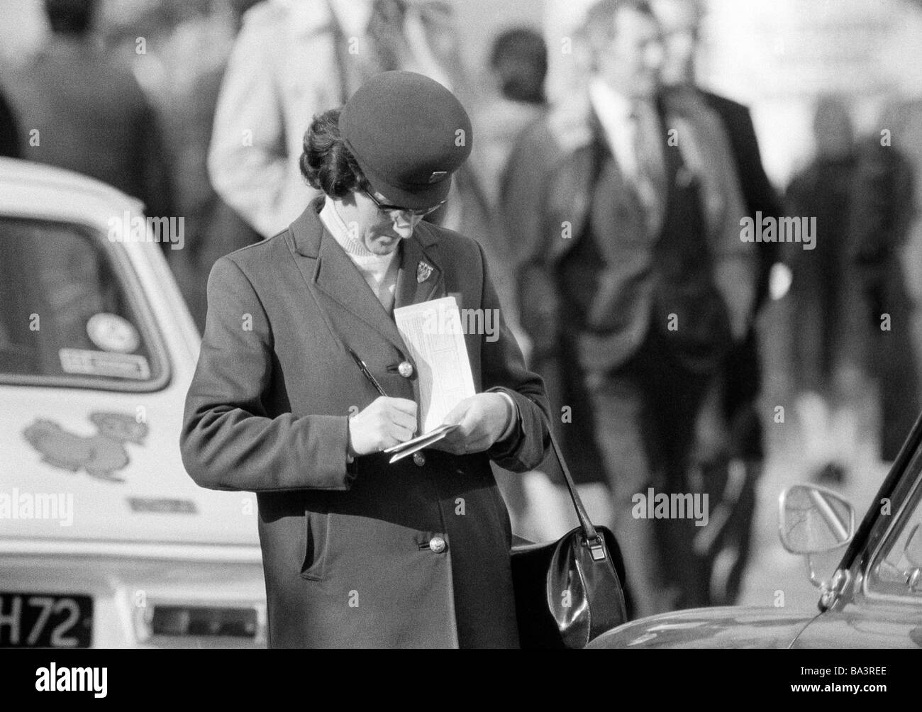 Seventies, black and white photo, road traffic, parking attendant writes a sticker though illegal parking, aged 40 to 50 years, France, Paris Stock Photo