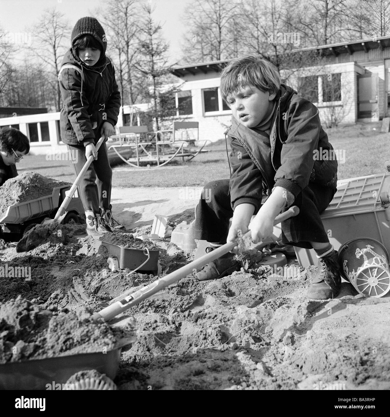 Seventies, black and white photo, people, physical handicap, school, study break, schoolyard, girl and boy play with shovels in a sandpit, aged 6 to 10 years, Special School Alsbachtal, D-Oberhausen, D-Oberhausen-Sterkrade, Ruhr area, North Rhine-Westphalia Stock Photo