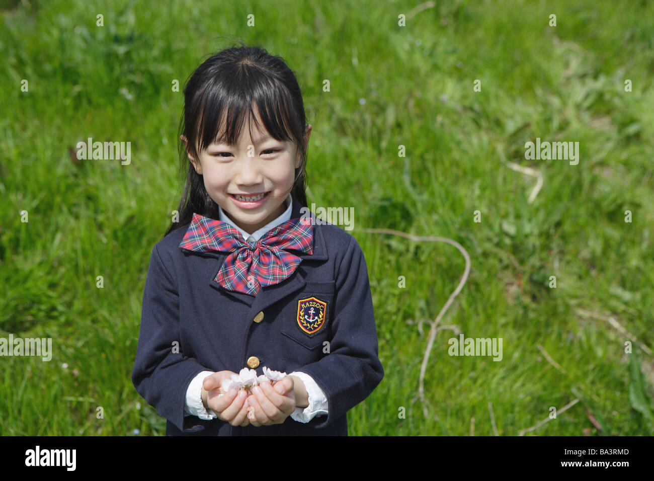 Japanese schoolgirl holding flowers in cupped hand Stock Photo