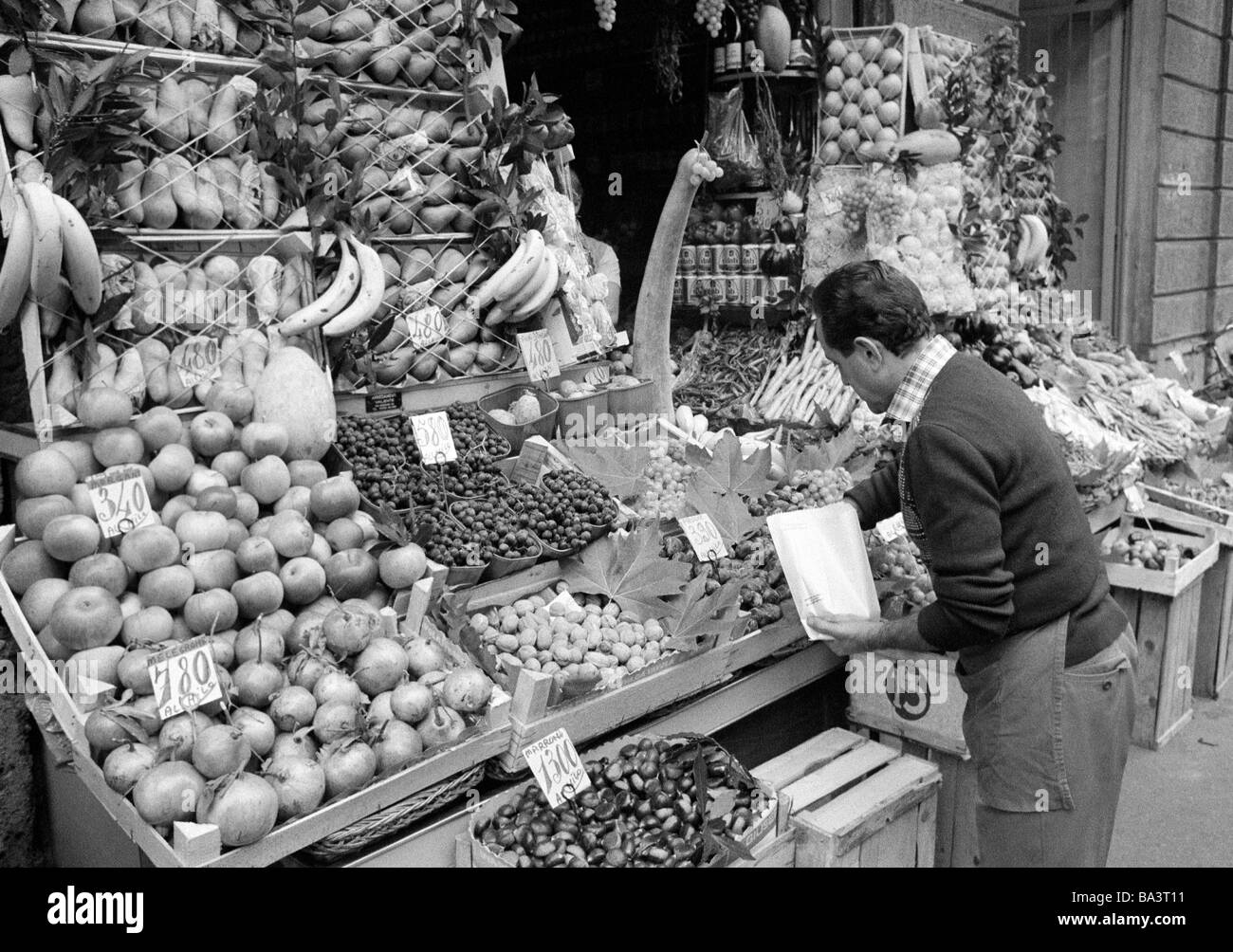Seventies, black and white photo, people, weekly market, market stall with fruit and vegetables, salesman, marketer, aged 40 to 50 years, Italy, Lombardy, Milan Stock Photo
