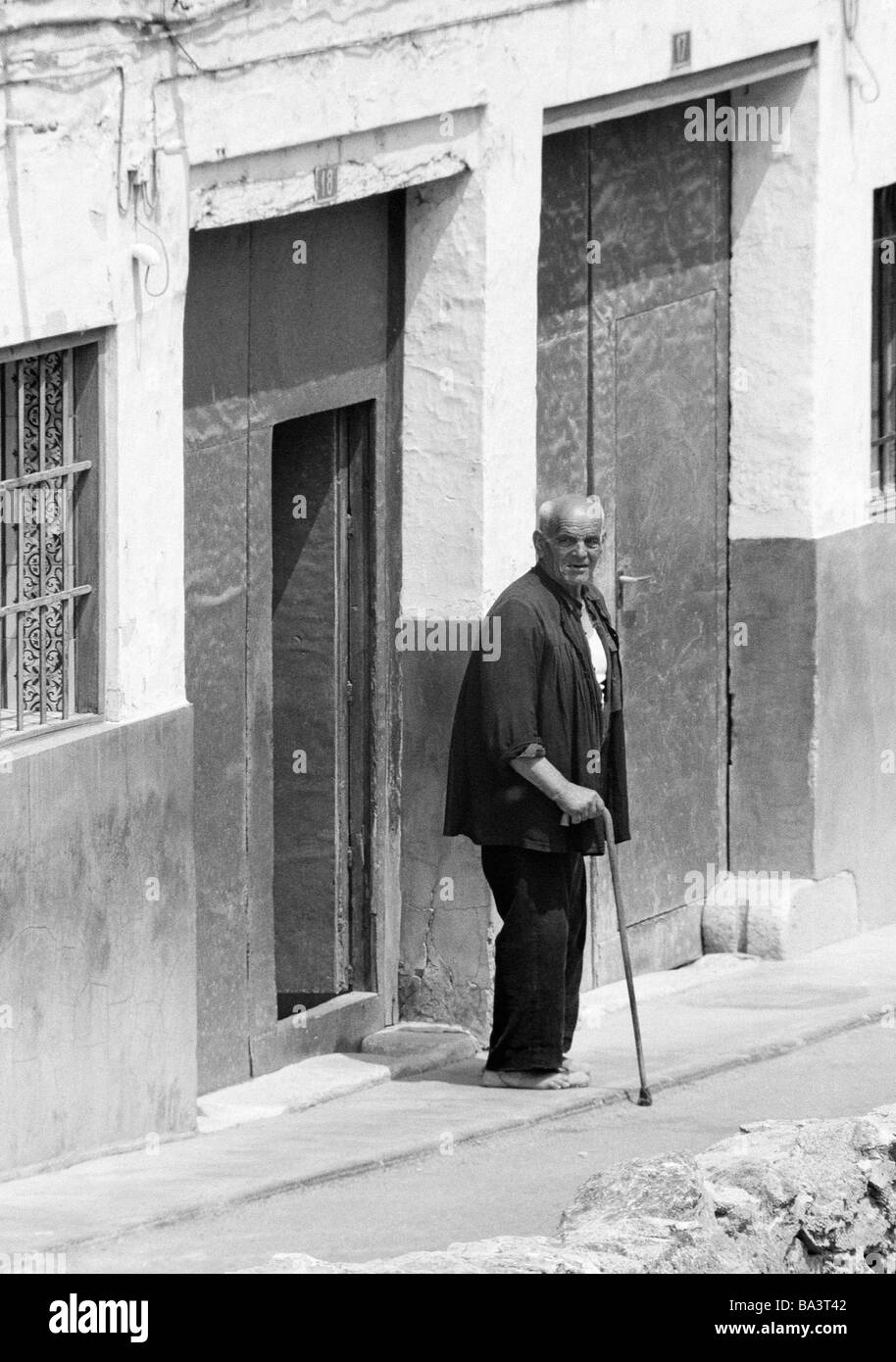 Seventies, black and white photo, people, older people, older man with a walking stick stands in front of a house door, barefooted, aged 70 to 80 years, Spain, Valencia Stock Photo