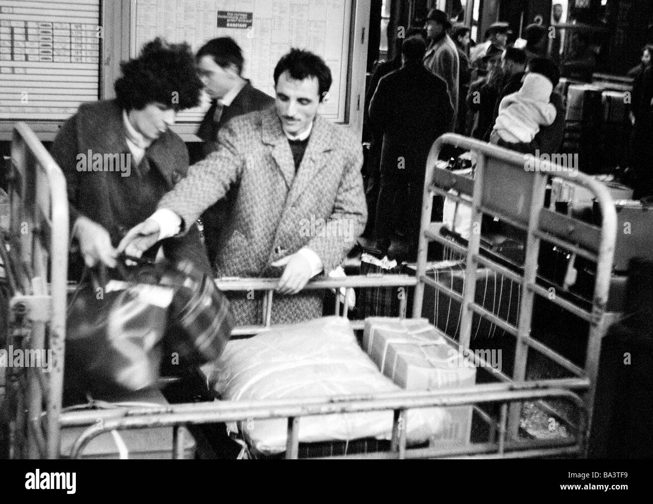 Sixties, black and white photo, people, business, guest-workers, an Italian guest-worker and his wife load a baggagecar in the central station of Dortmund for their homeward journey to Italy at Christmas, aged 30 to 40 years, D-Dortmund, Ruhr area, North Rhine-Westphalia Stock Photo