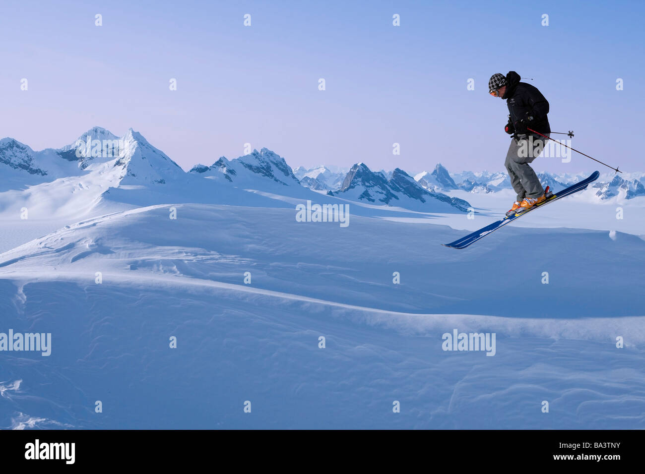 Alpine skier making a jump with the Juneau Ice Field and Rhino Peak in the background in Southeast Alaska. Composite Stock Photo