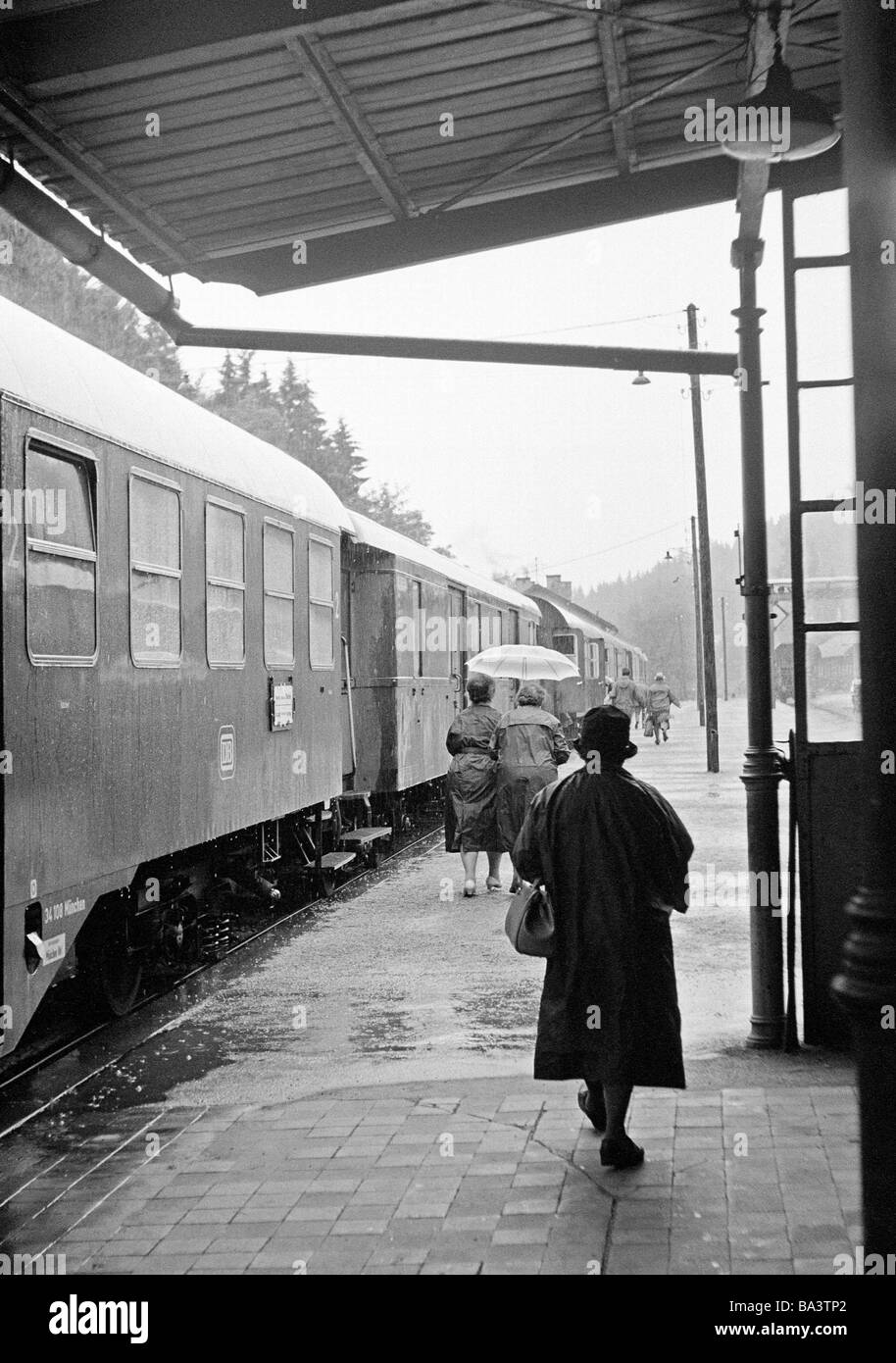 Sixties black and white photo people senior older woman walks on a platform to the waiting train station coat hat handbag aged 60 to 70 years