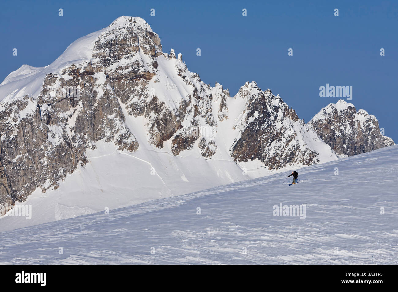 Alpine skier skiing on the Juneau Ice Field and Rhino Peak in the background in Southeast Alaska. Composite Stock Photo
