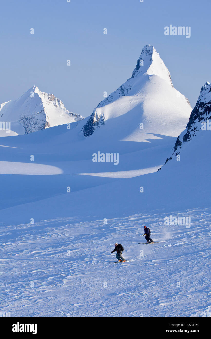 Alpine skiers skiing on the Juneau Ice Field and Rhino Peak in the background in Southeast Alaska. Composite Stock Photo