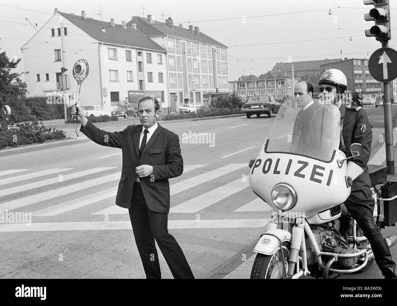 Seventies, black and white photo, traffic, police check, traffic control at a cebra crossing, police officer lifts the signalling disc, beside a policeman on his motorbike, aged 30 to 40 years, D-Bottrop, Ruhr area, North Rhine-Westphalia Stock Photo