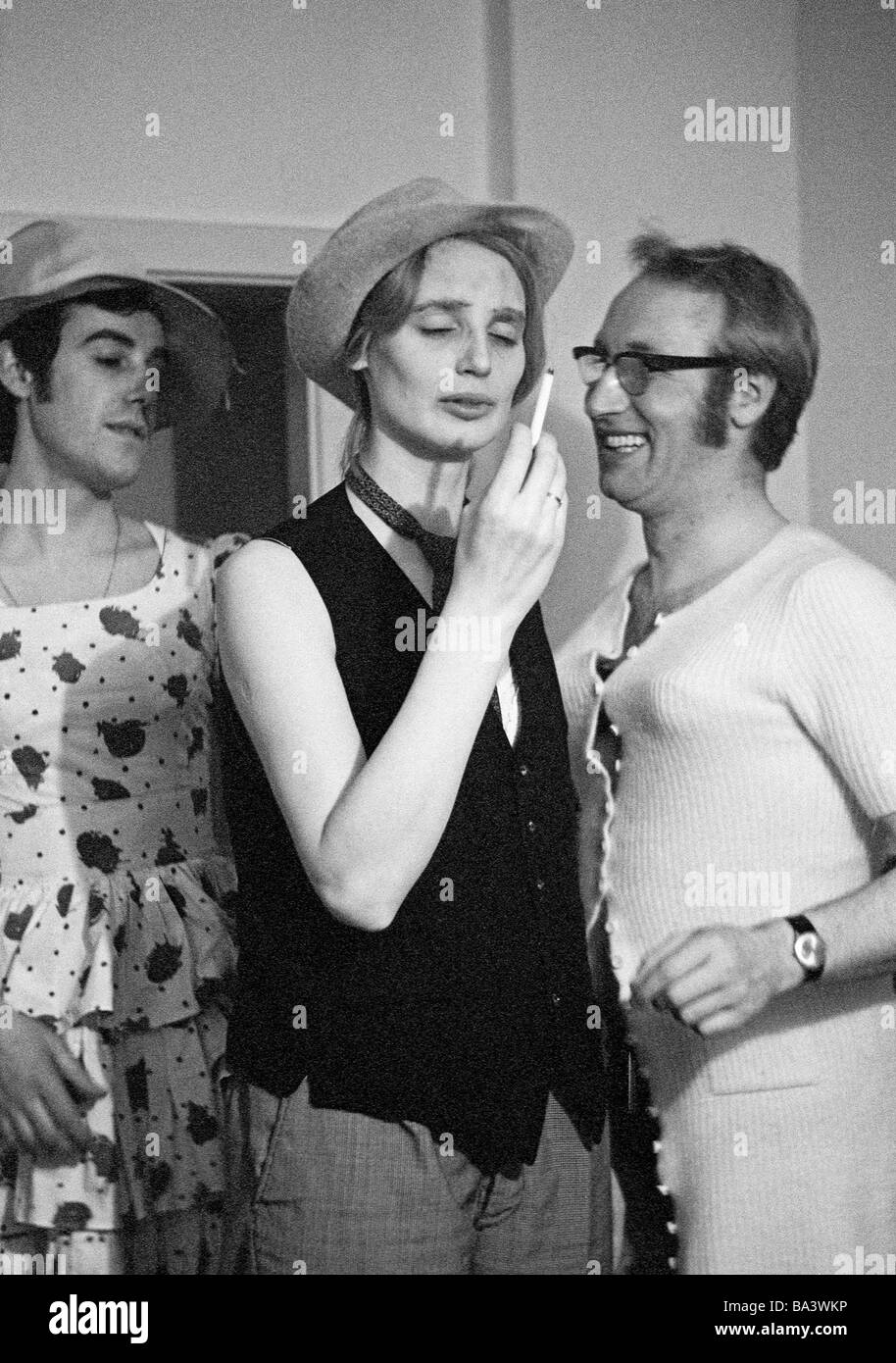Seventies, black and white photo, humour, people, carnival, fancy-dress party, young woman disguised as a man holding a cigarette, two young men in womens clothing, ruched dress, aged 20 to 30 years, Margret, Werner Stock Photo