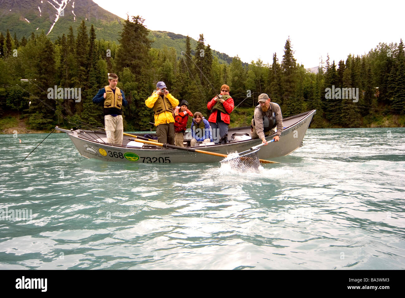 Woman battling trout on Kenai River from drift boat Kenai Peninsula Alaska Summer Stock Photo