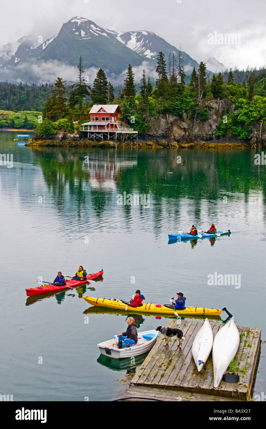 Kayakers pass by a floating dock in Halibut Cove in Kachemak Bay