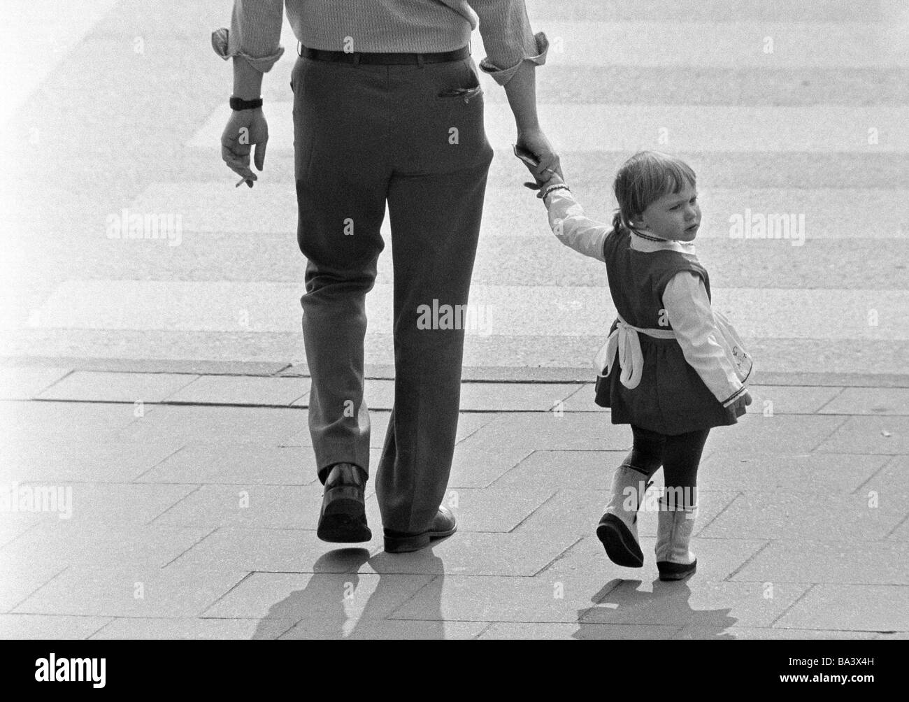 Seventies, black and white photo, people, father takes a walk with the little daughter, zebra crossing, aged 25 to 30 years, aged 3 to 4 years Stock Photo