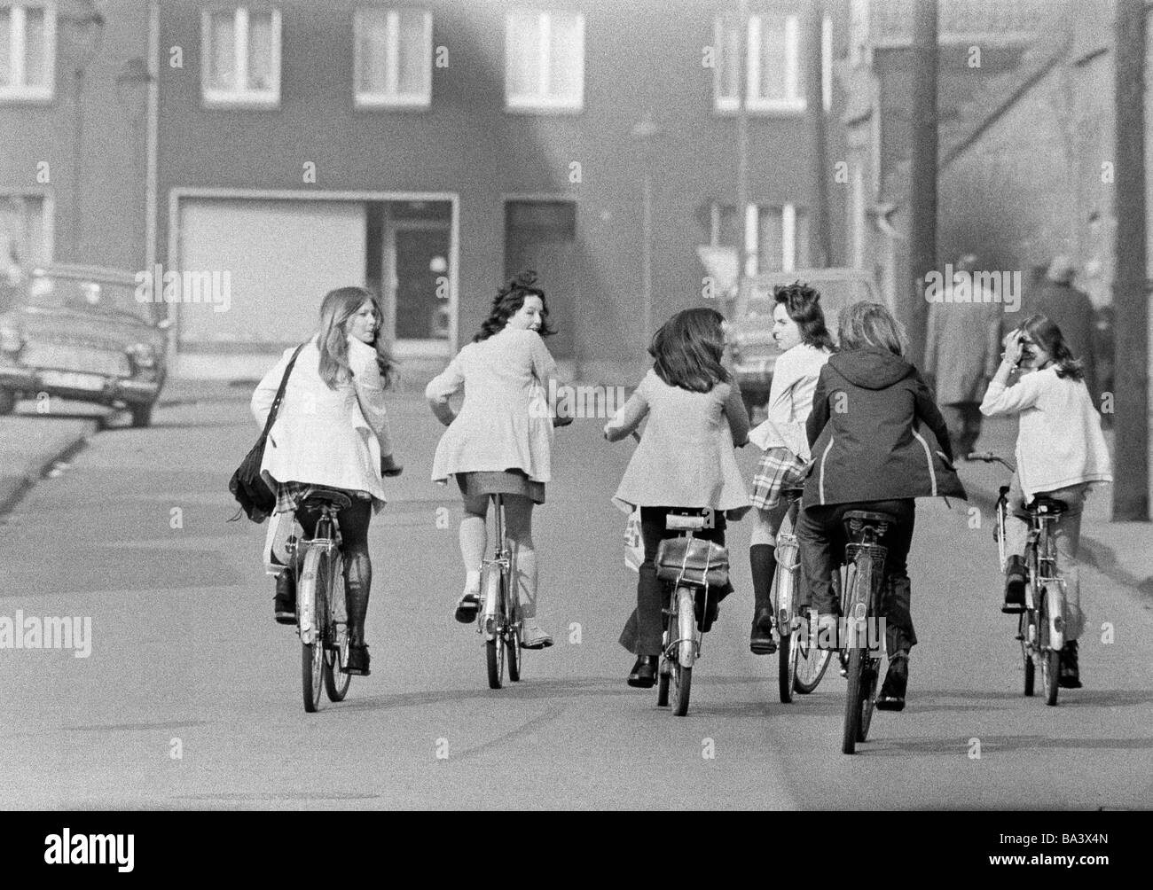 Seventies, black and white photo, people, six young girls on bicycles drive side by on a traffic road, pleasure trip, excursion, aged 13 to 16 years Stock Photo