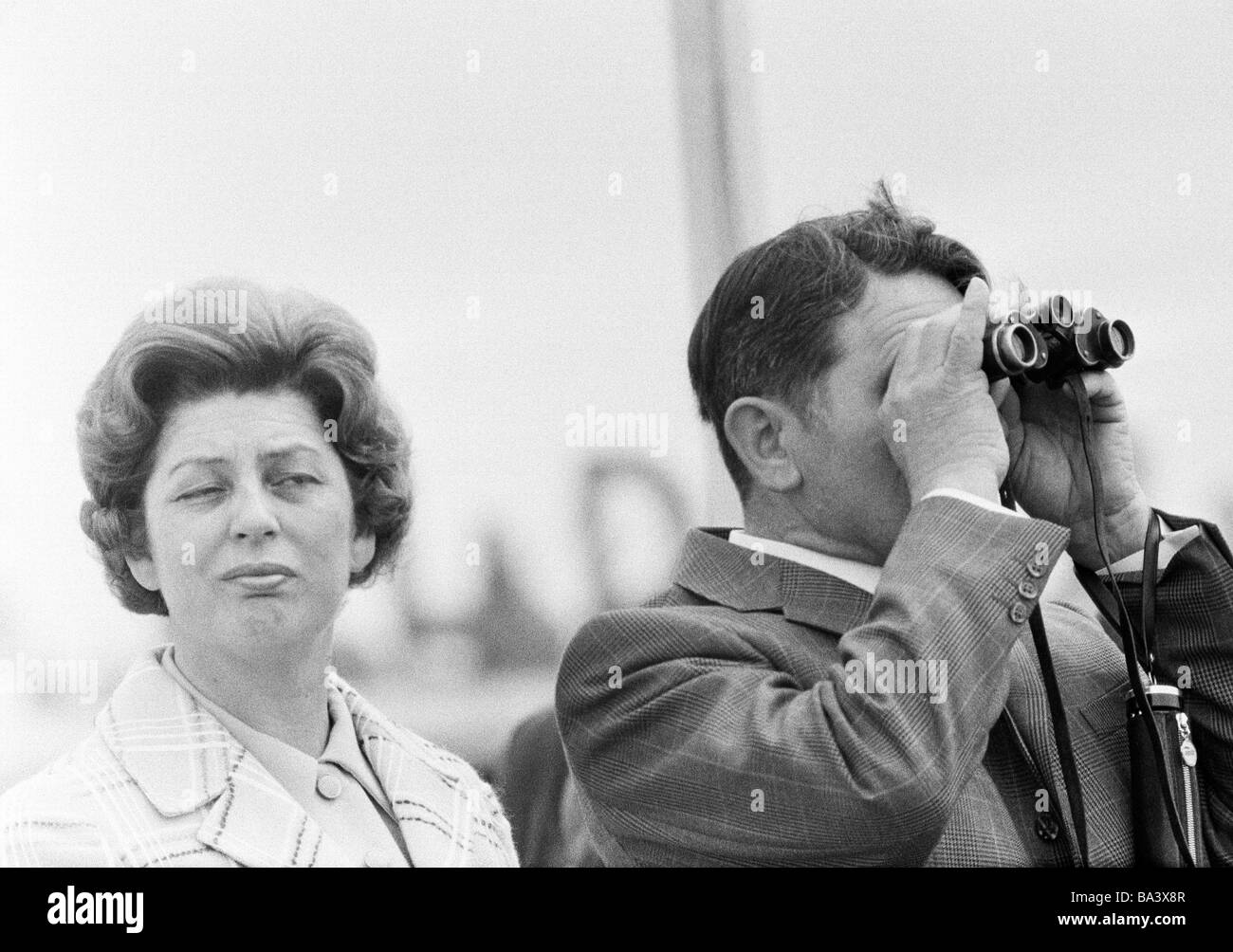 Seventies, black and white photo, people, couple, freetime, contrasts, interest, boredom, man looks through a binoculars, woman is bored, aged 40 to 50 years Stock Photo