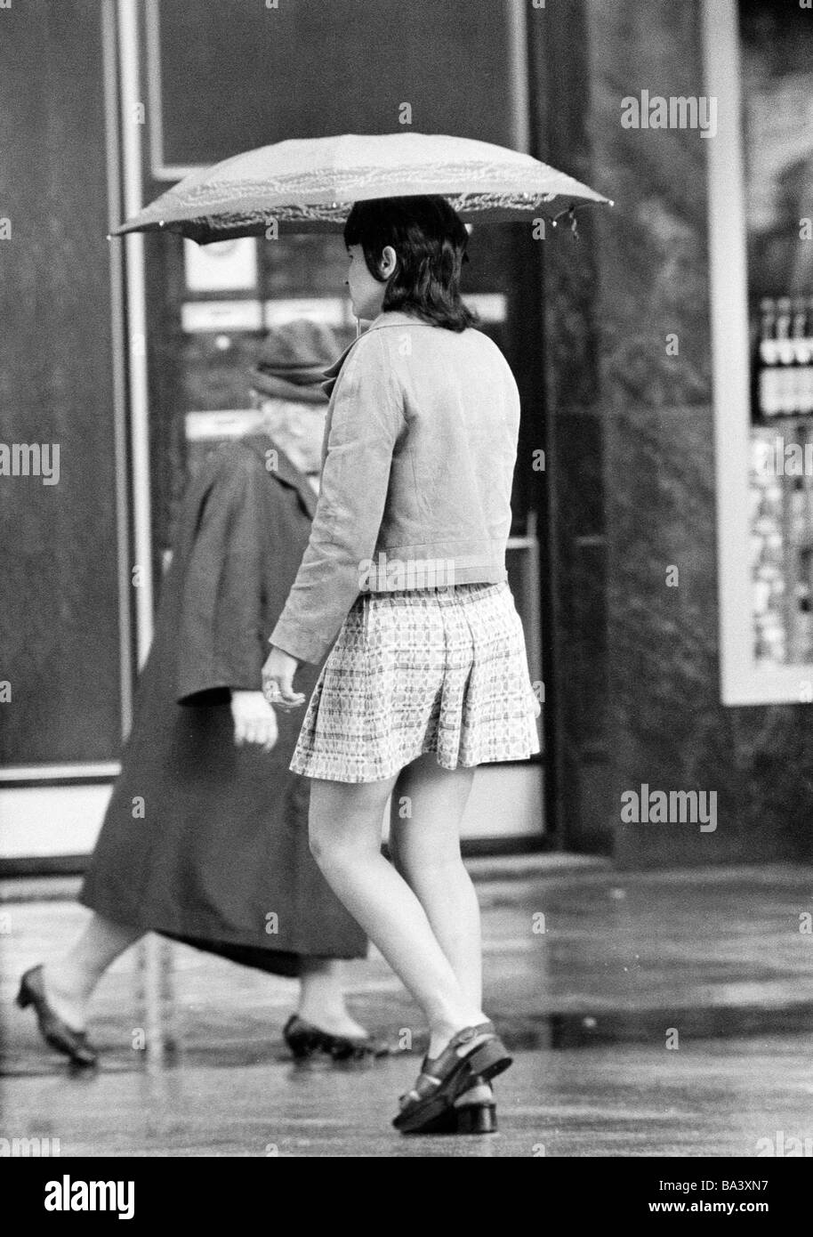 Seventies, black and white photo, weather, rain, young woman under an umbrella, aged 20 to 25 years Stock Photo