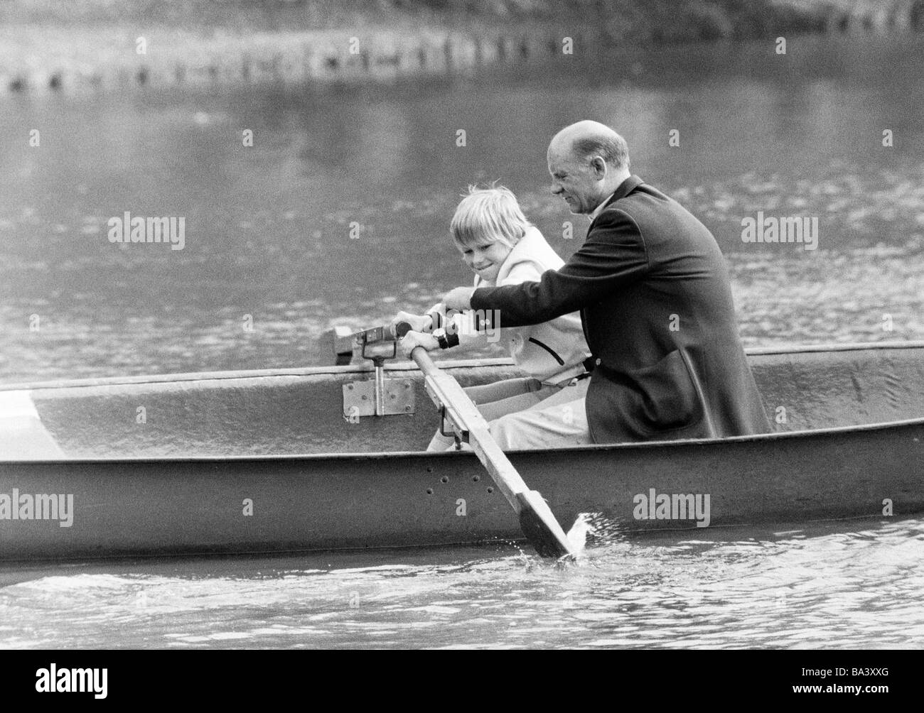 Seventies, black and white photo, people, older man with grandchild in a rowing boat, aged 55 to 65 years, aged 6 to 8 years Stock Photo
